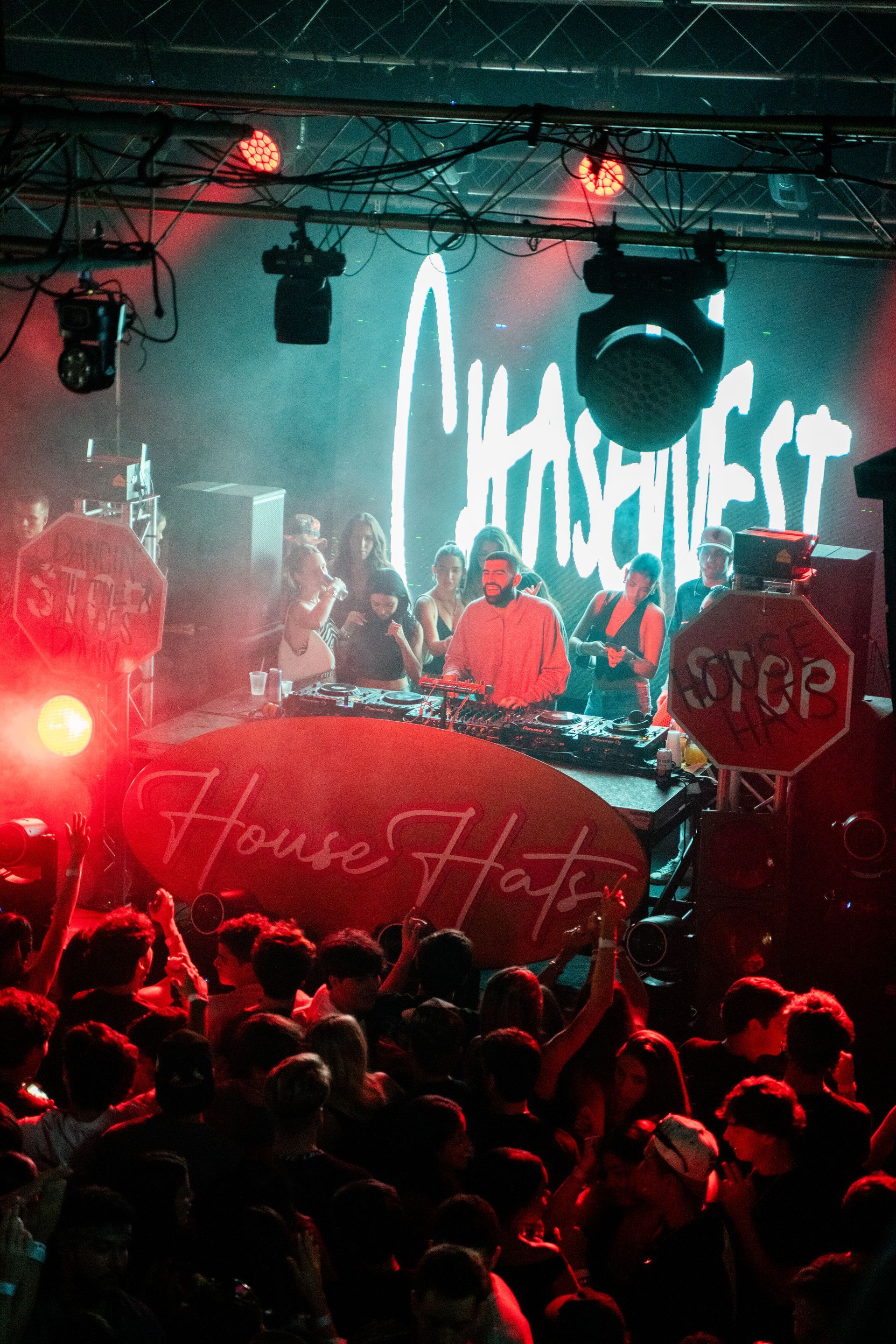 A crowd of people are dancing in a club with a stop sign in the foreground.