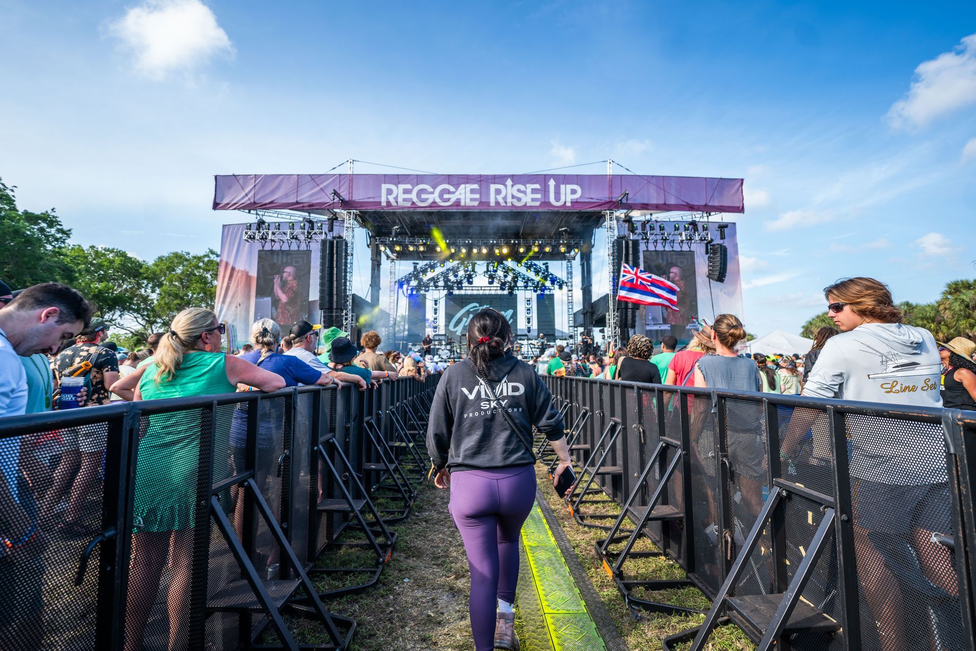 A woman is walking towards a stage at a music festival.