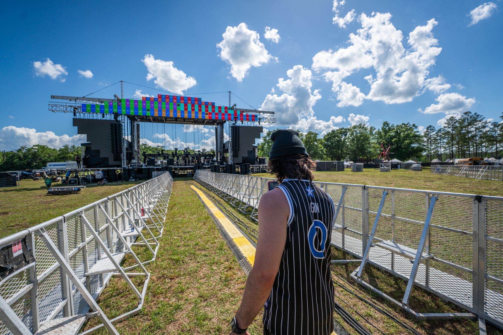 A man is standing in front of a stage at a music festival.