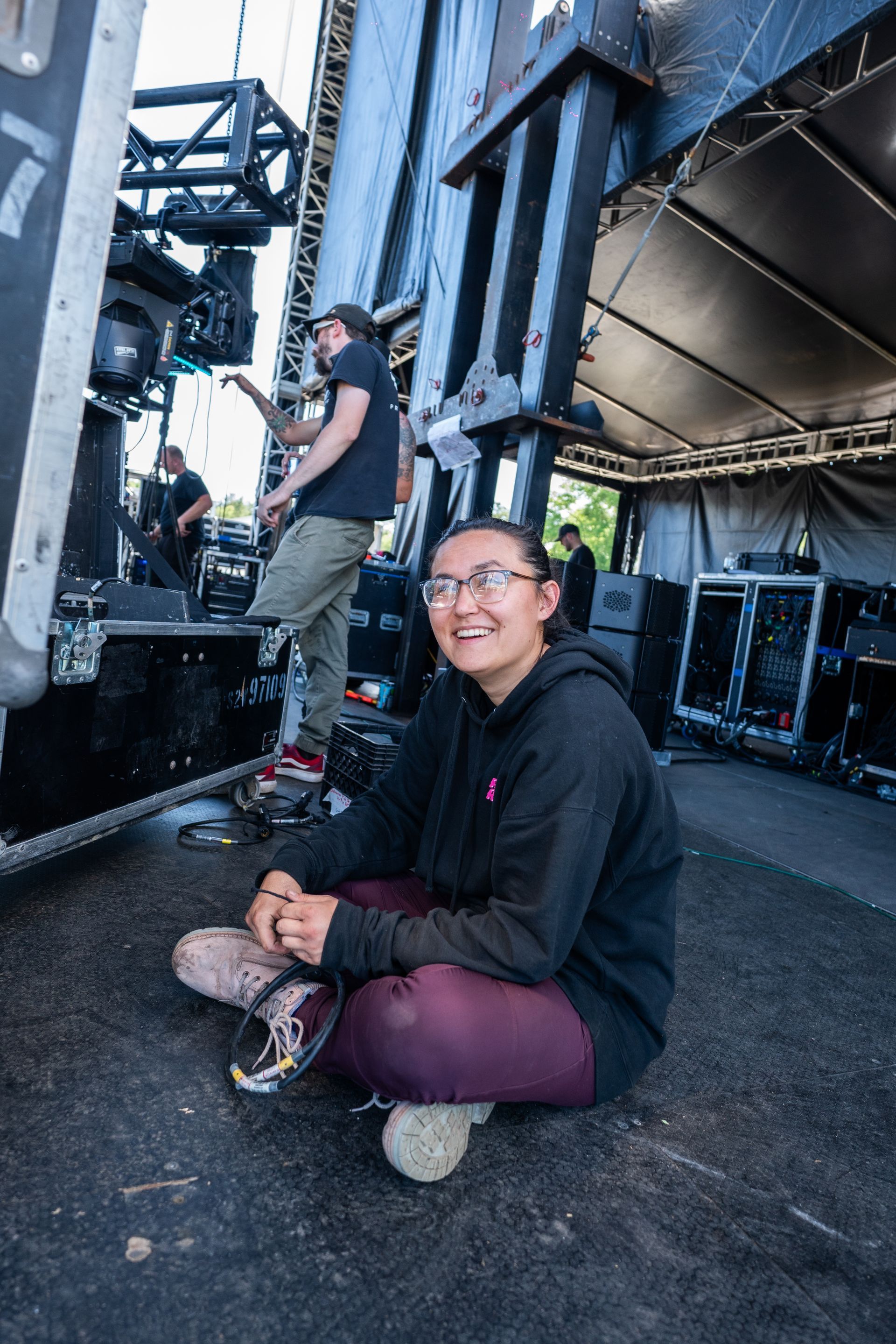 A woman is sitting on the ground in front of a stage.