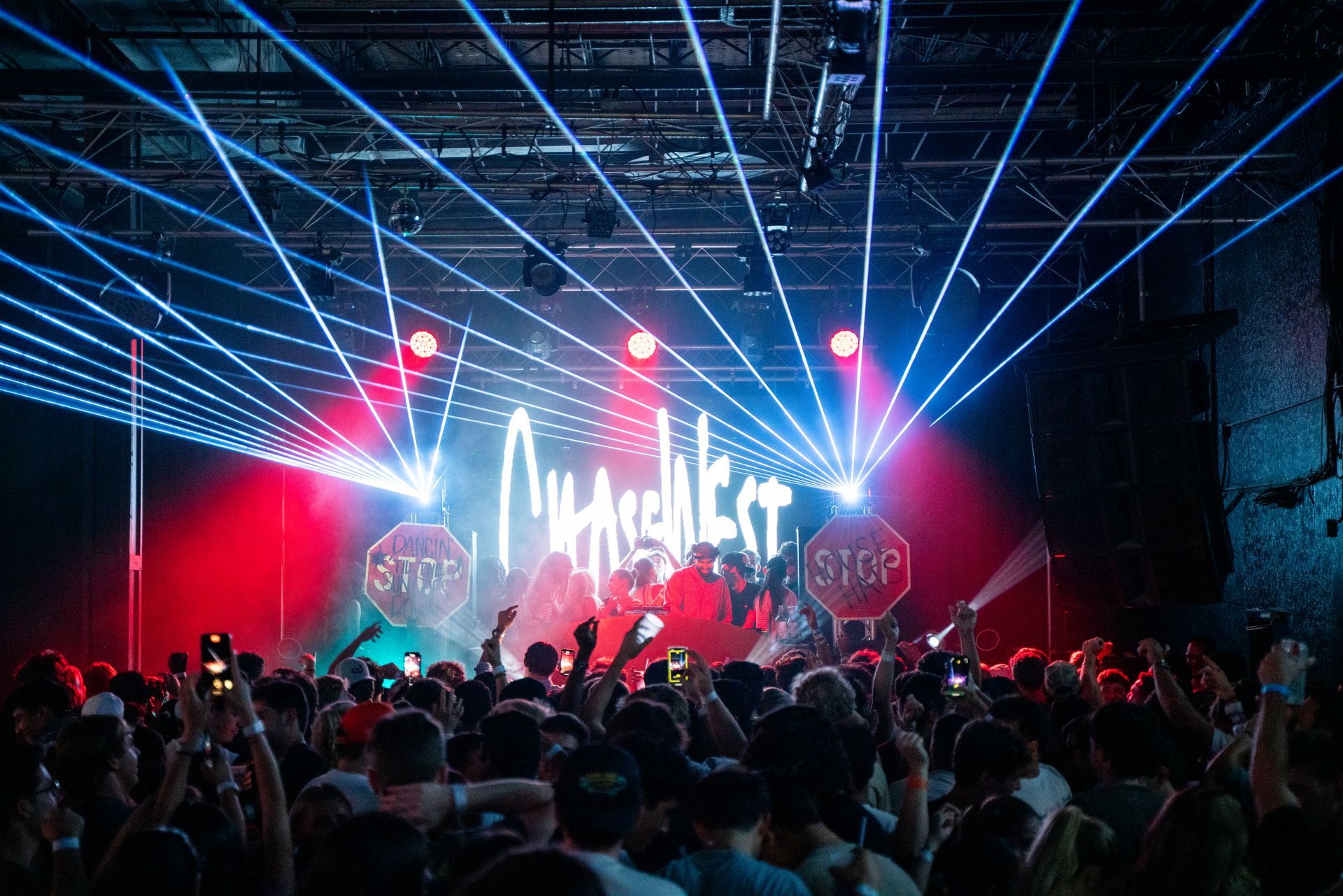 A crowd of people at a concert with a stop sign on the stage