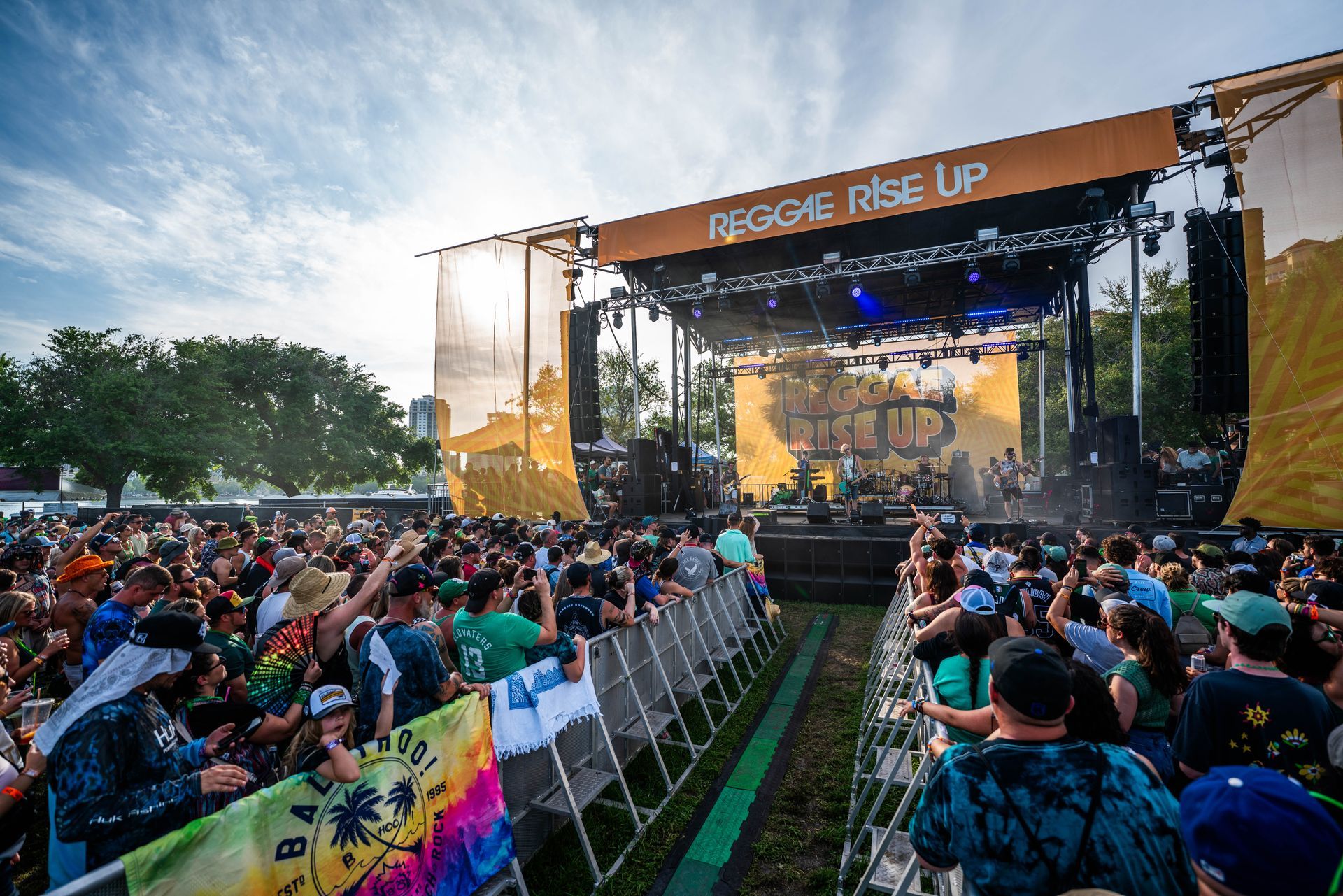 A crowd of people are standing in front of a stage at a music festival.