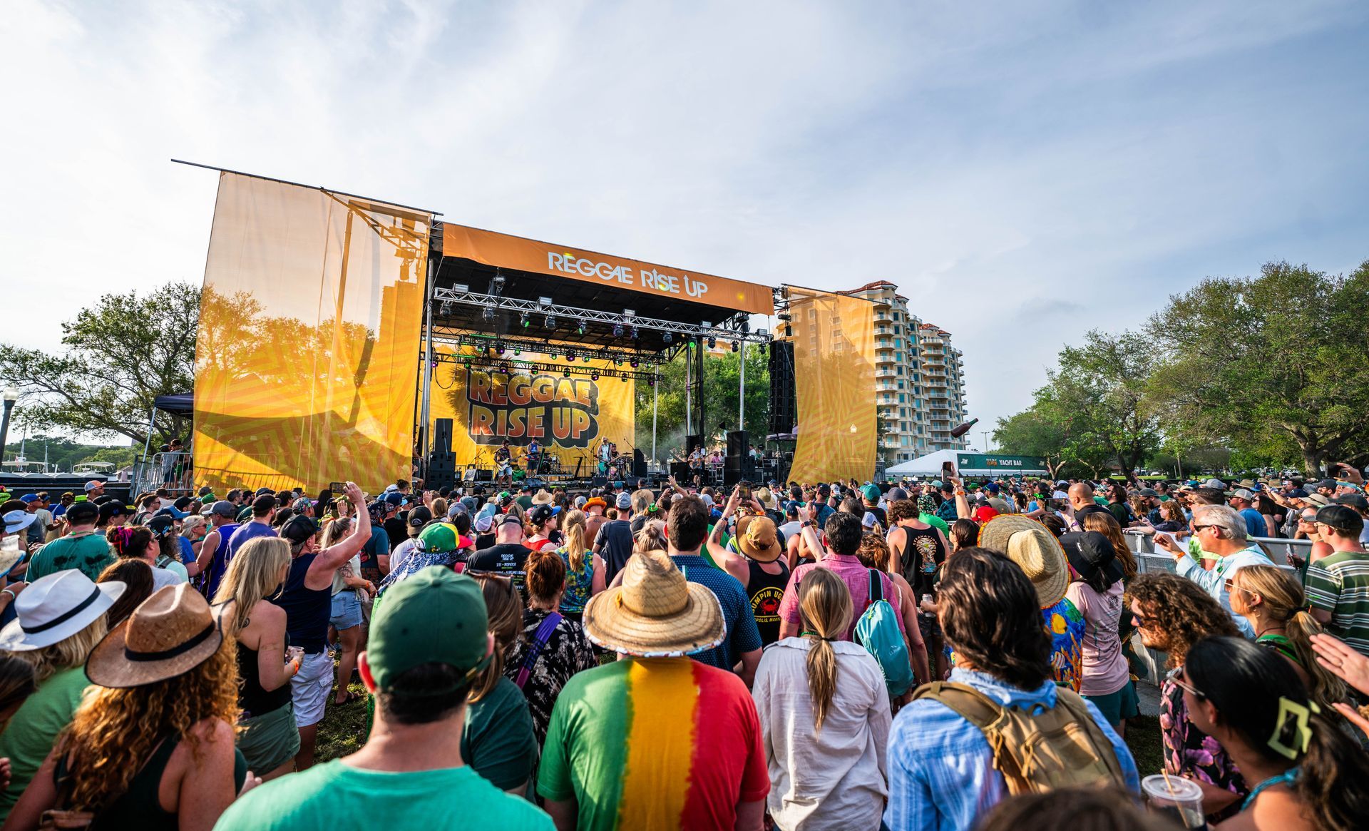 A crowd of people are standing in front of a stage at a music festival.