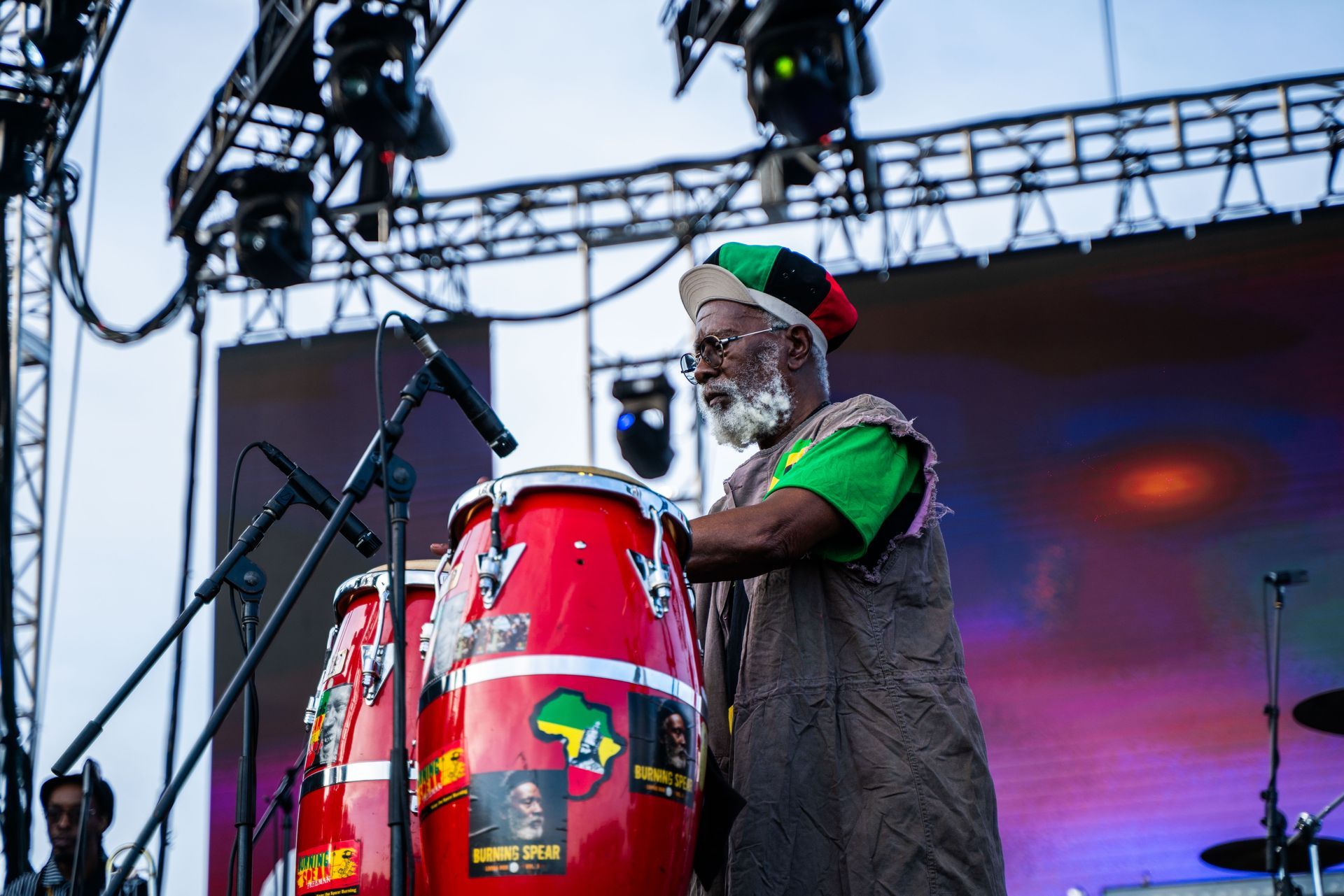 A man is playing drums on a stage in front of a microphone.