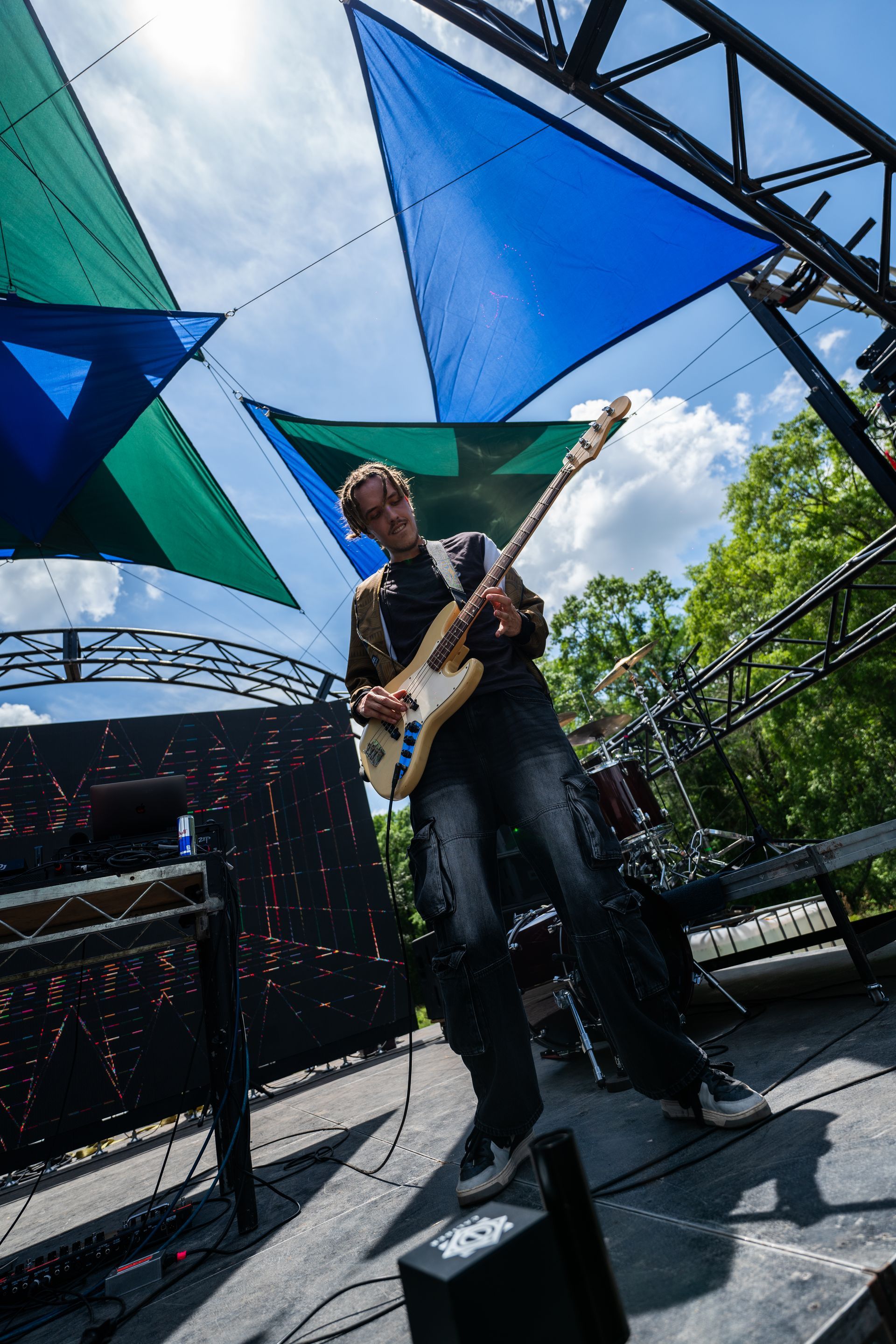 A man is playing a guitar on a stage under a blue canopy.
