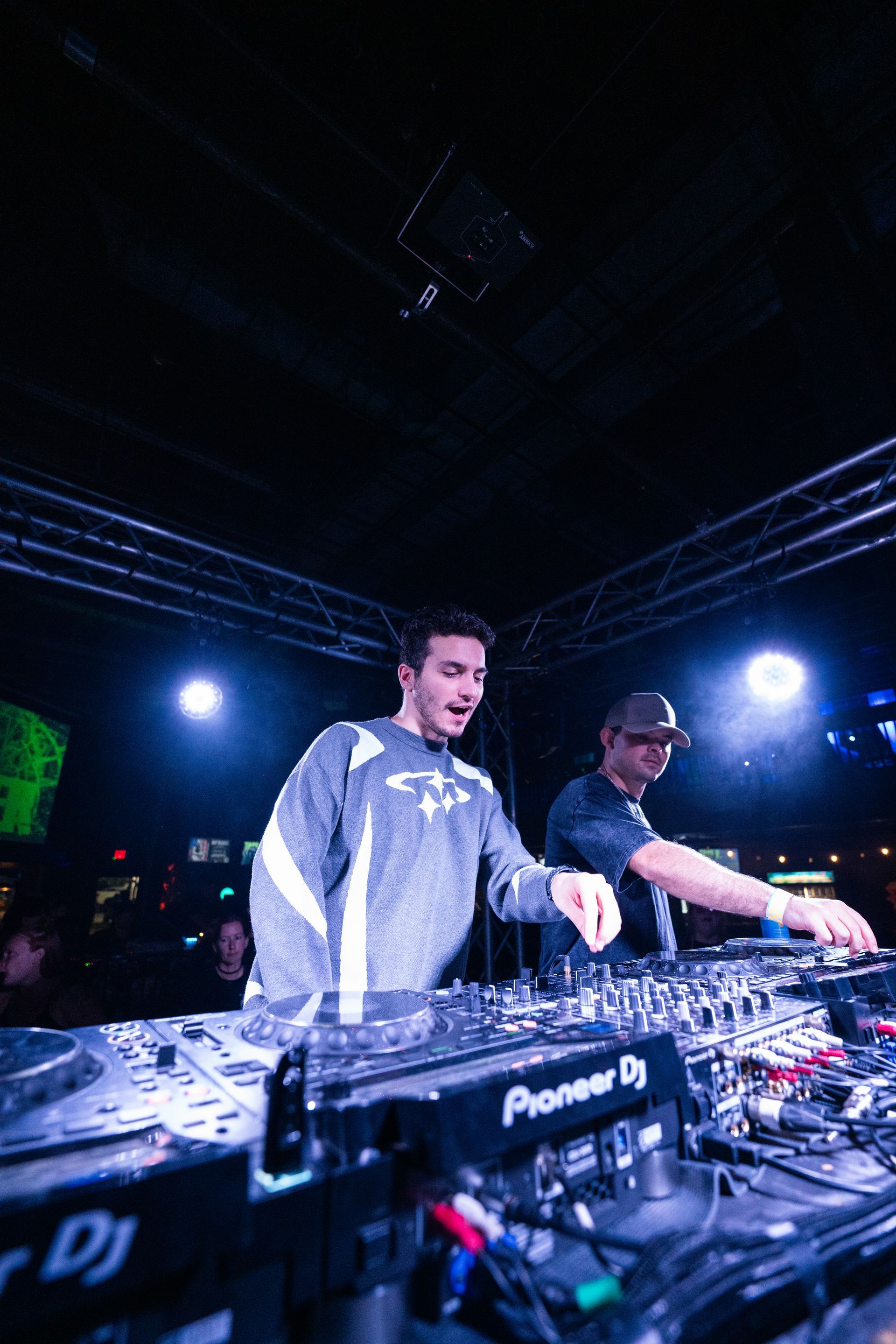 Two men are playing music on pioneer dj equipment in a dark room.