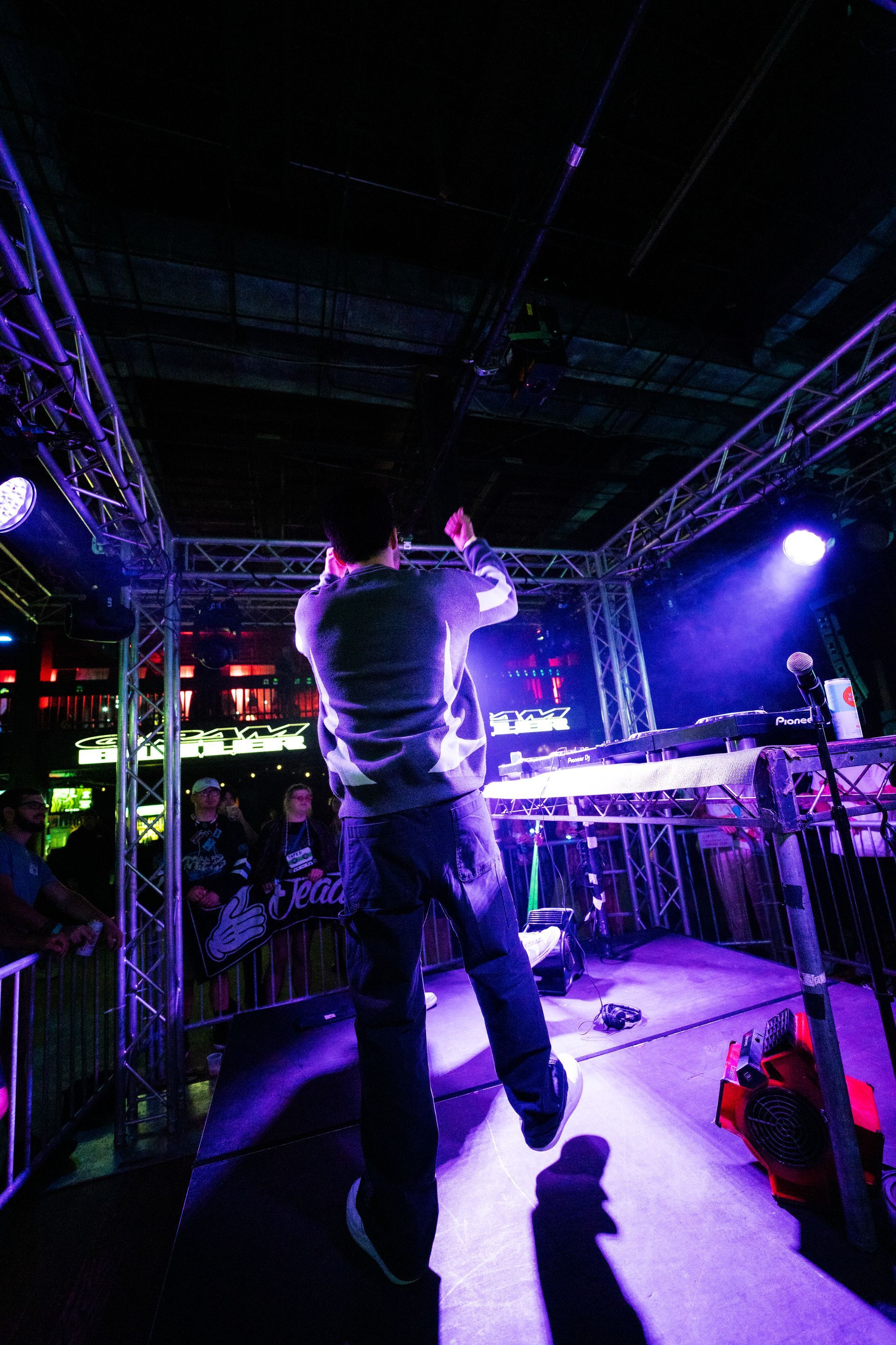 A man is standing on a stage in a dark room with purple lights.