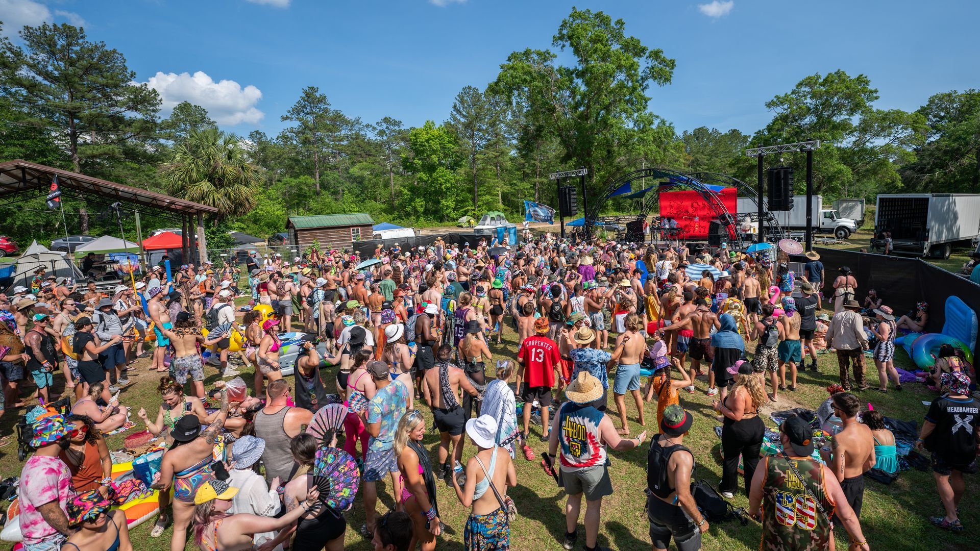 A large group of people are standing in a field at a festival.