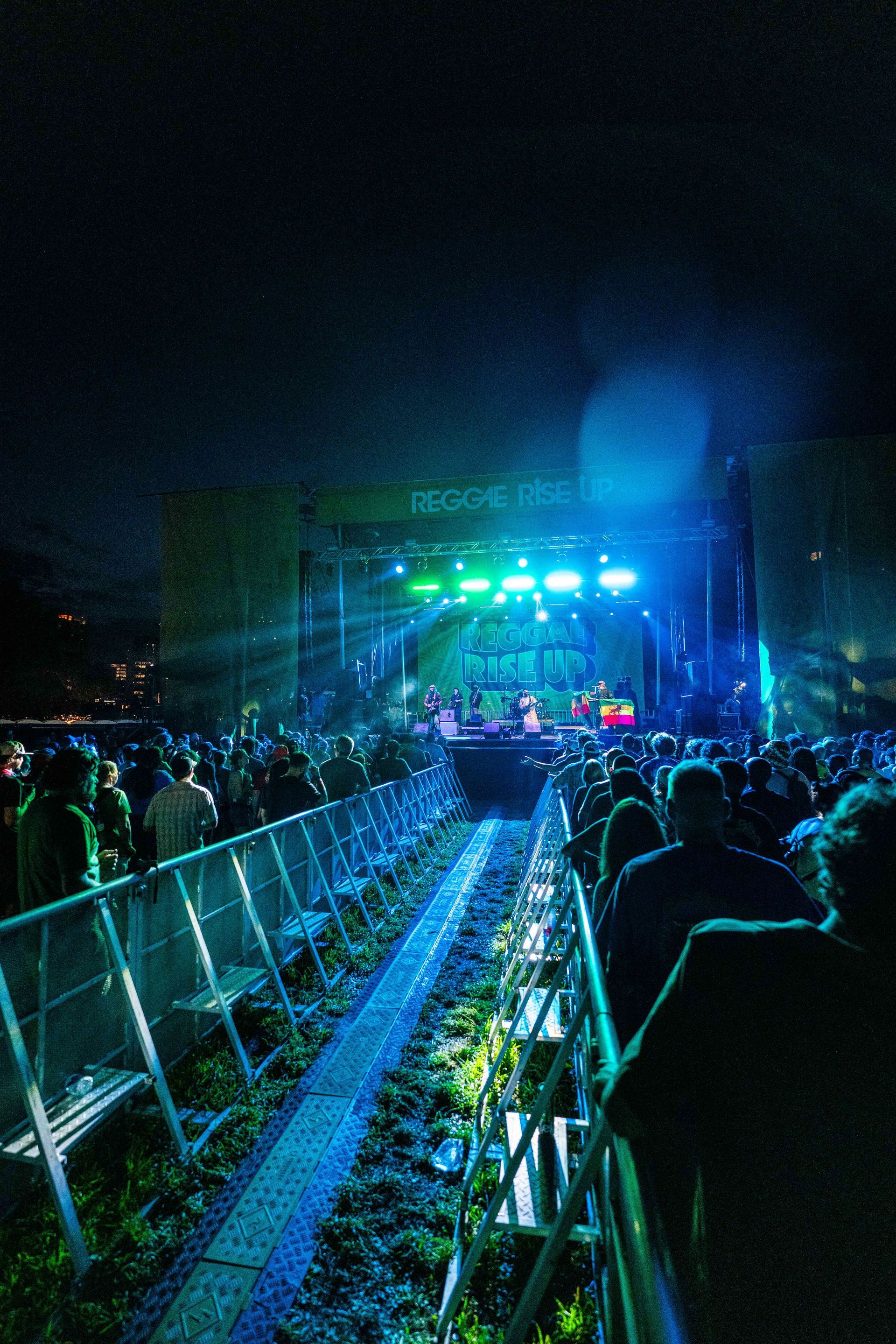 A crowd of people watching a concert with a sign that says music city