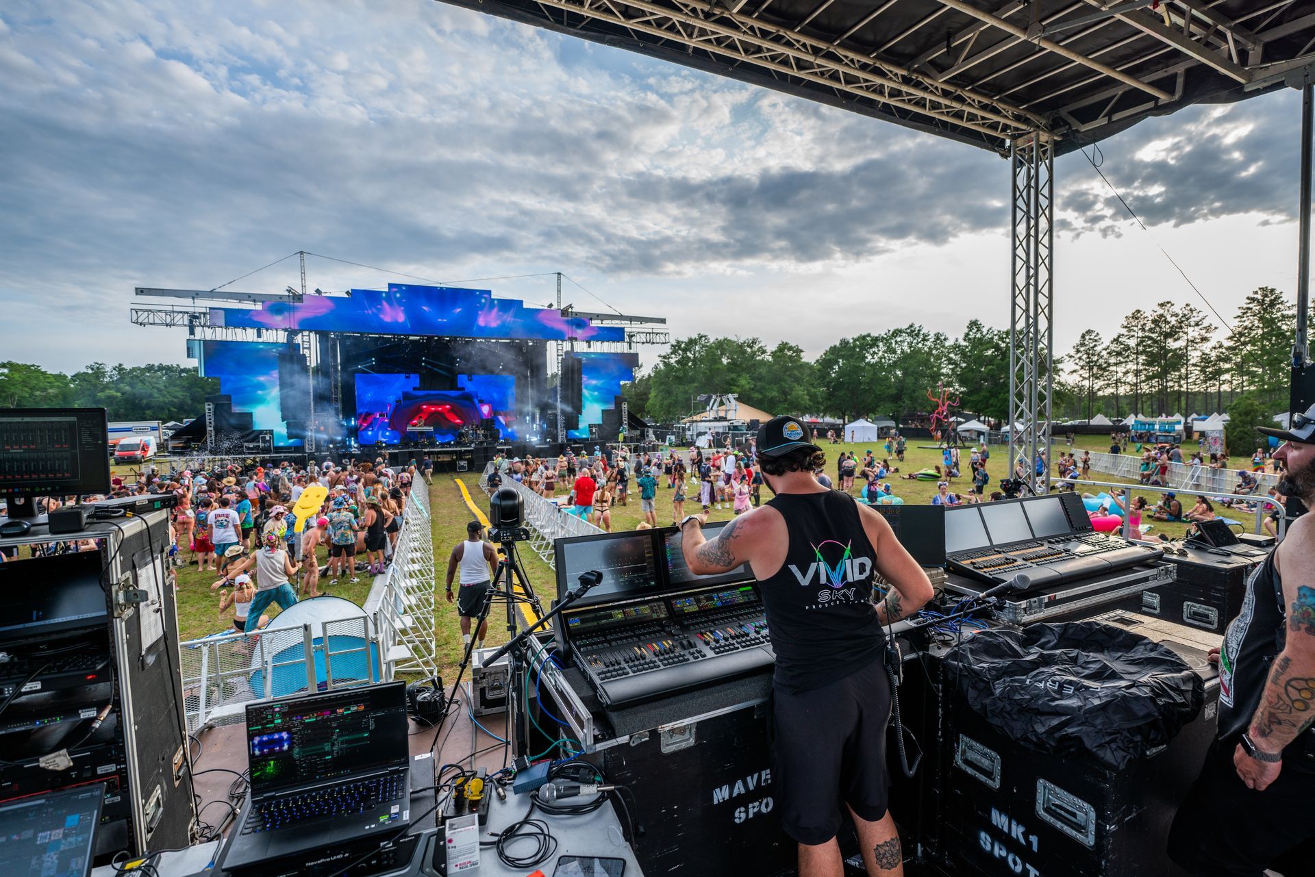 A man is standing in front of a stage at a music festival.