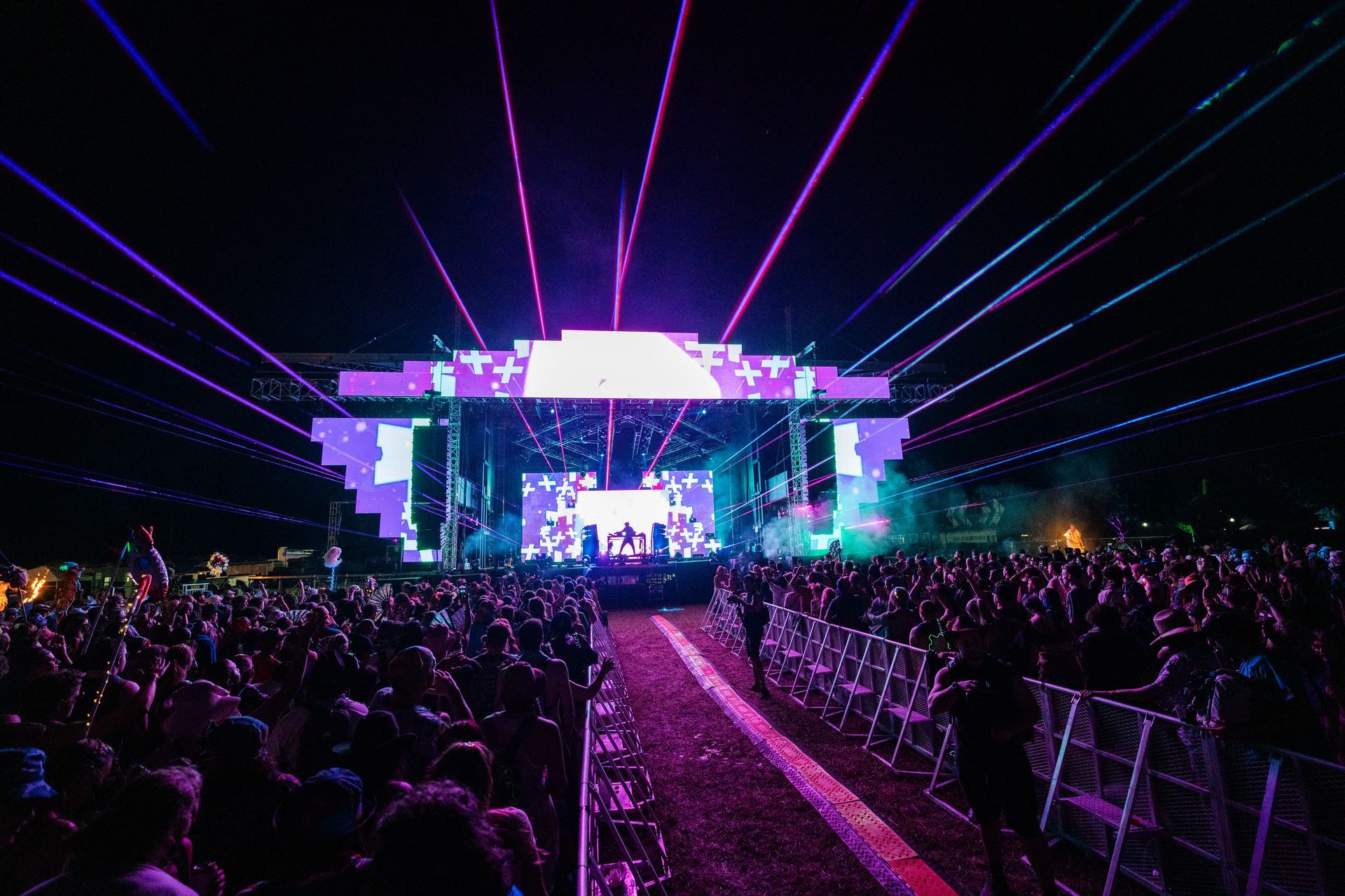 A crowd of people are standing in front of a stage at a concert.