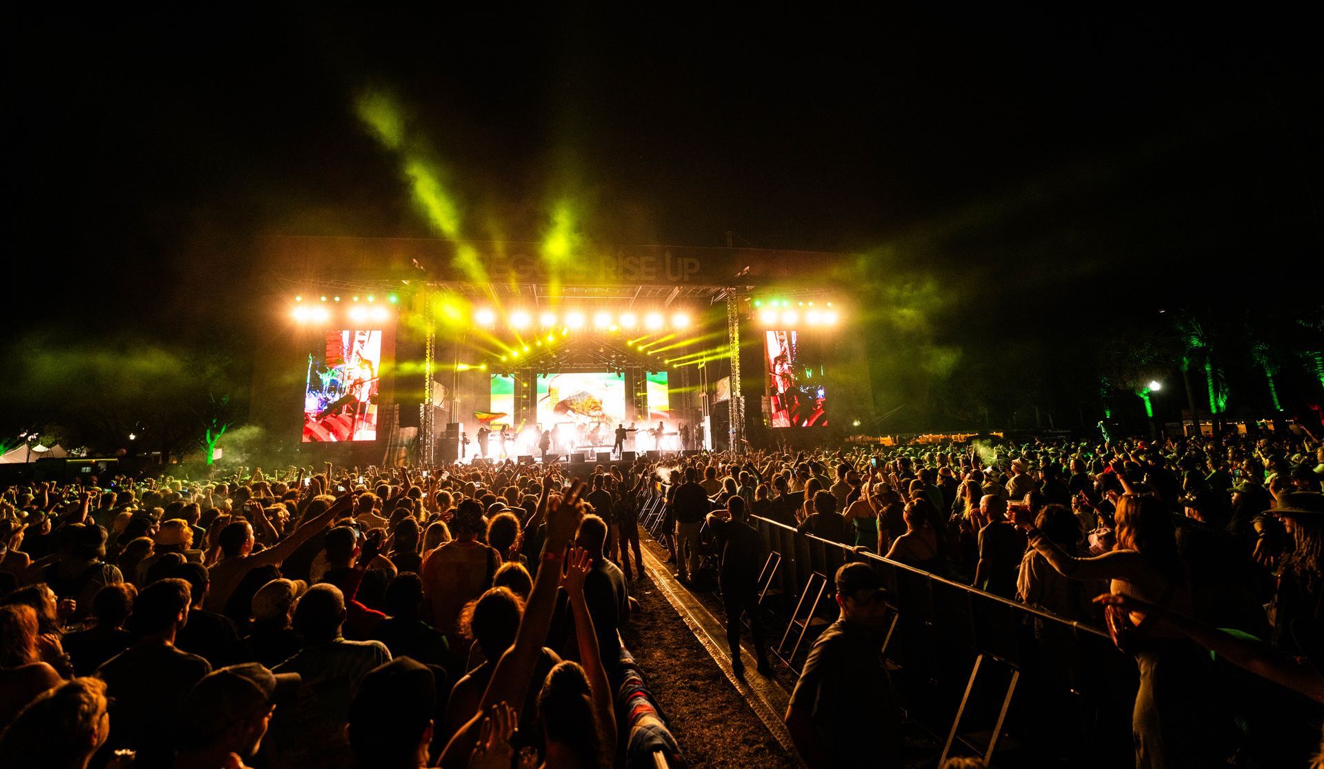A crowd of people are watching a concert at night.