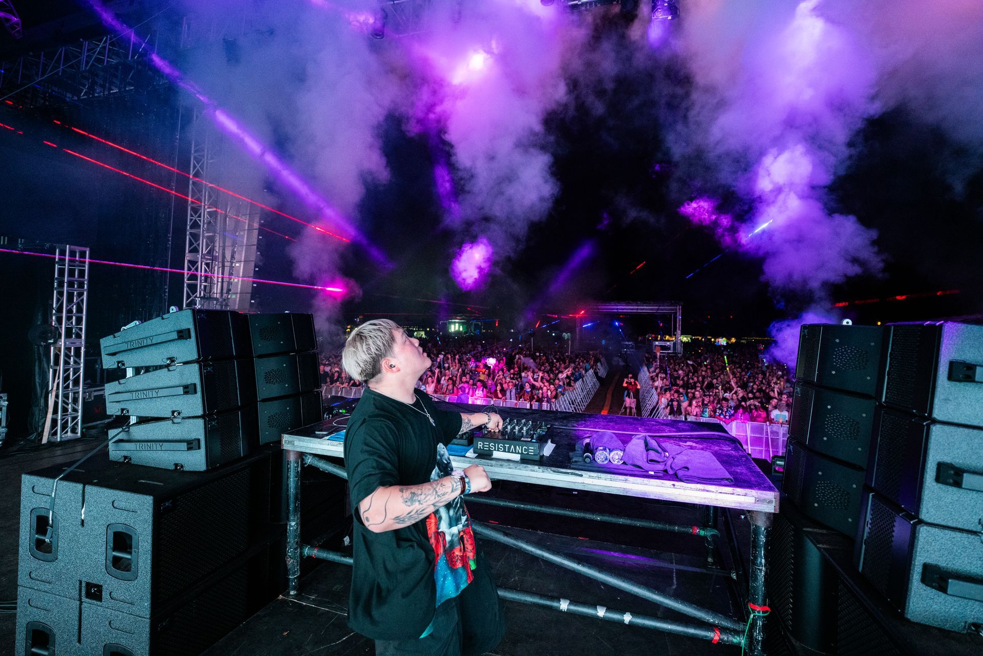 A dj is playing music on a stage in front of a crowd.