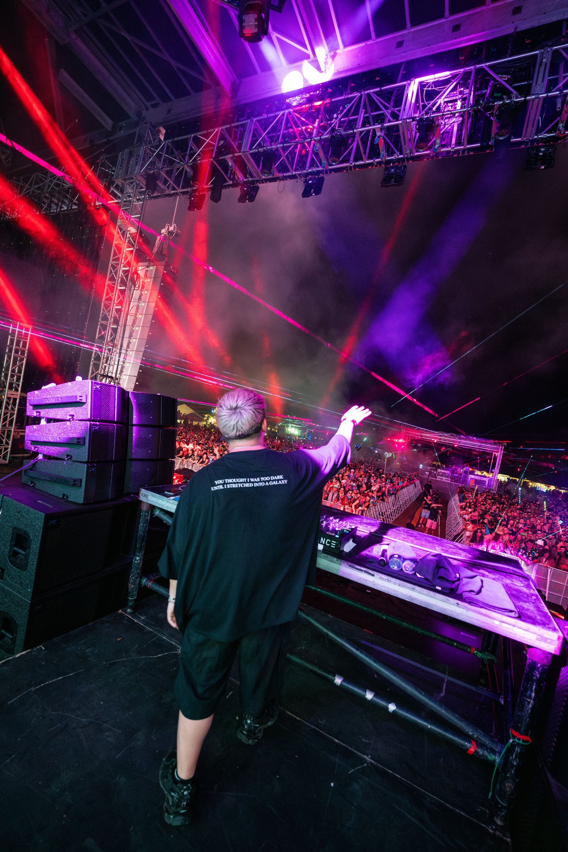 A man is standing on a stage in front of a crowd at a concert.
