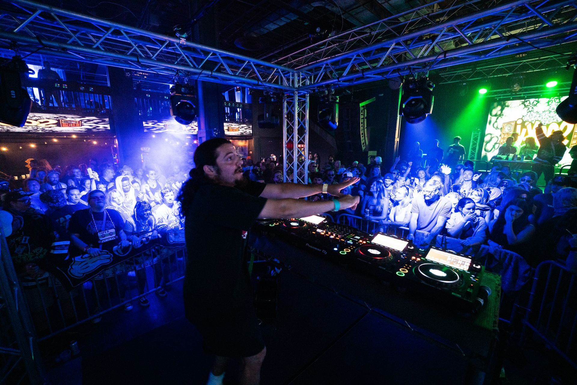 A man is playing a dj set in front of a crowd in a club.