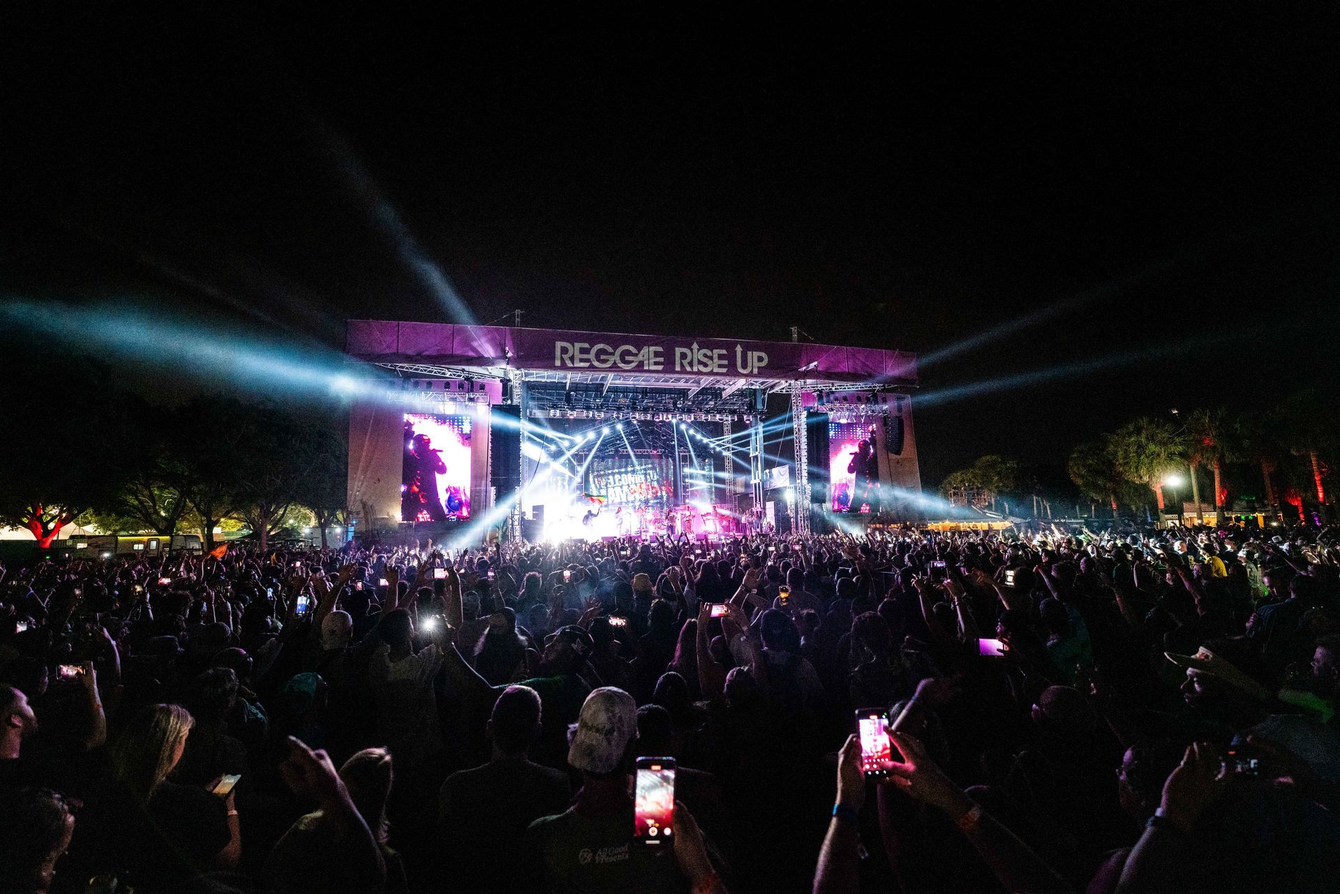 A crowd of people are standing in front of a stage at a concert.