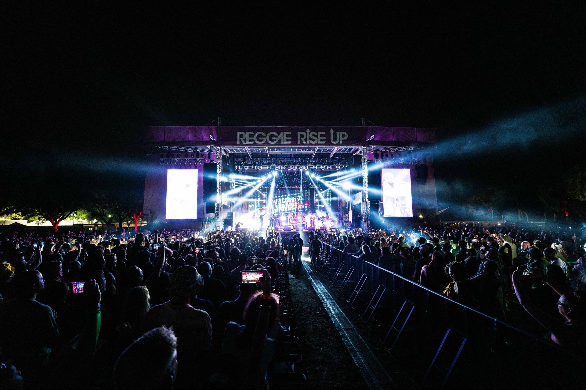 A crowd of people are standing in front of a stage at a concert.