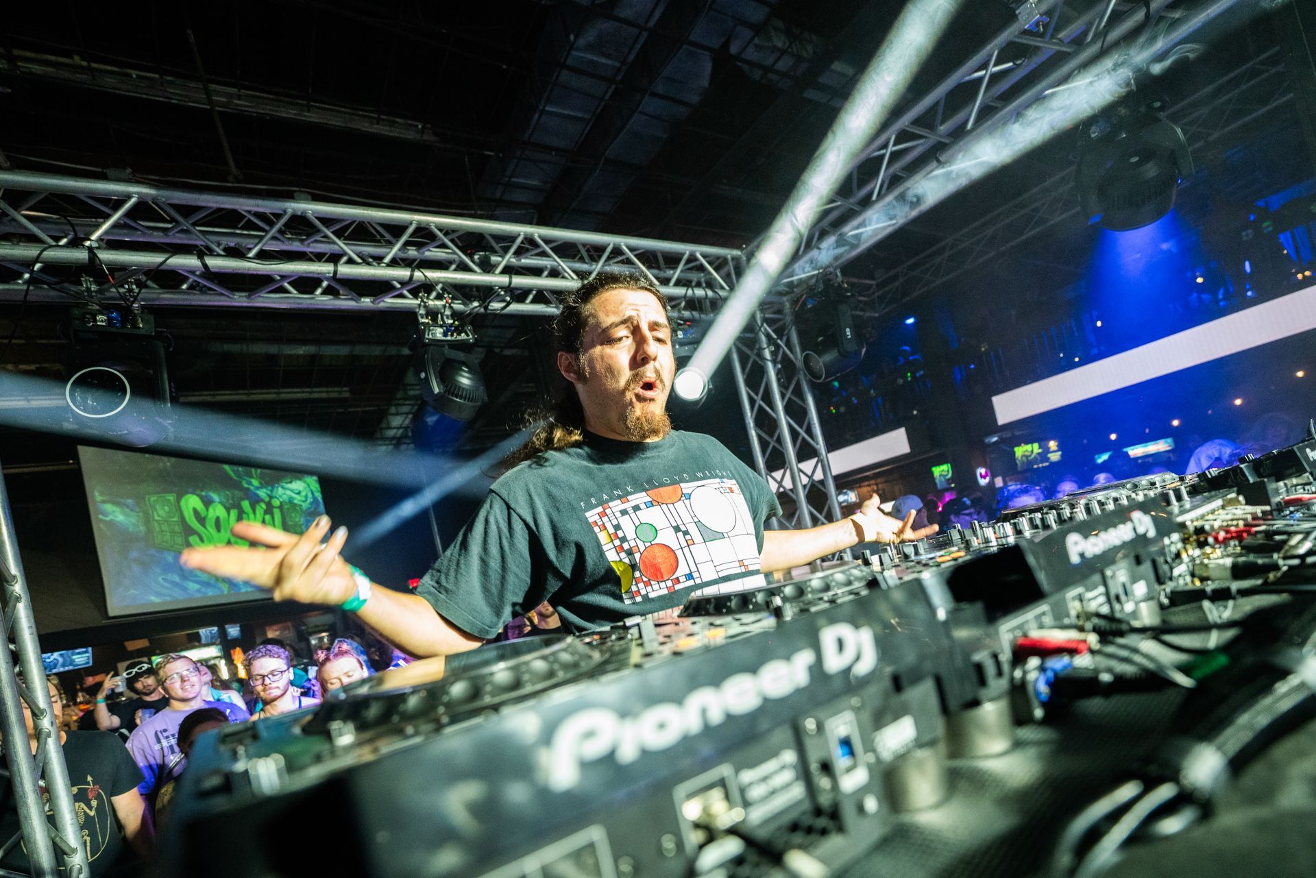 A man is standing in front of a pioneer dj controller on a stage.