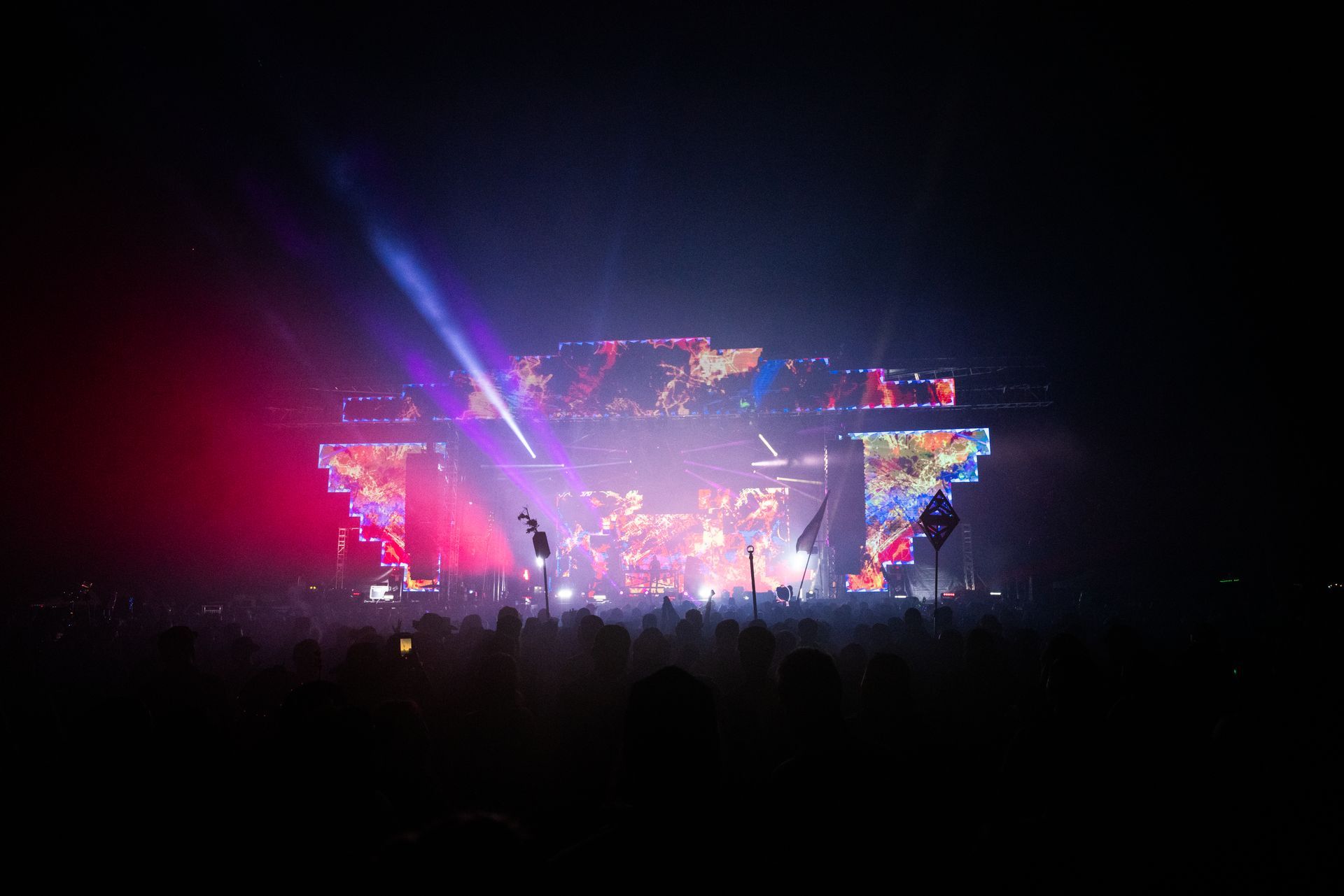 A crowd of people are standing in front of a stage at a concert.