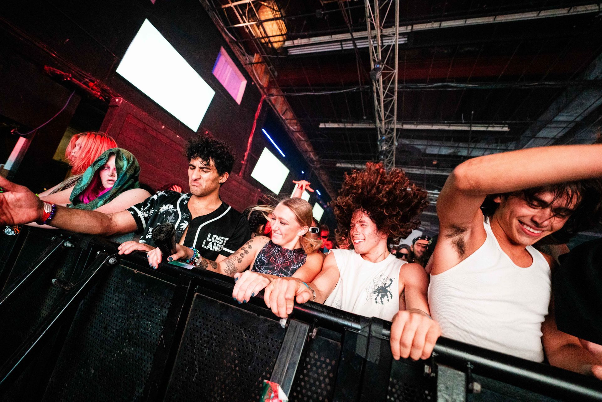 A group of people are standing behind a fence at a concert.