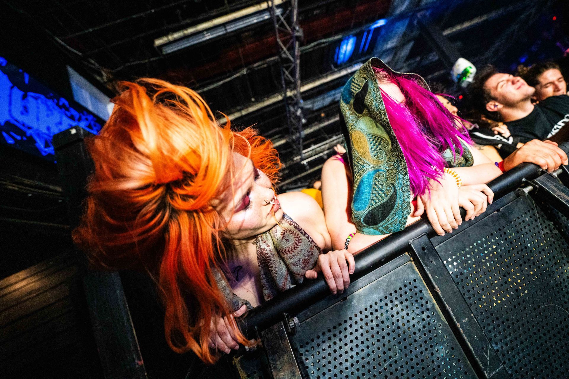 A group of people are sitting in a dark room and one of them has pink hair.