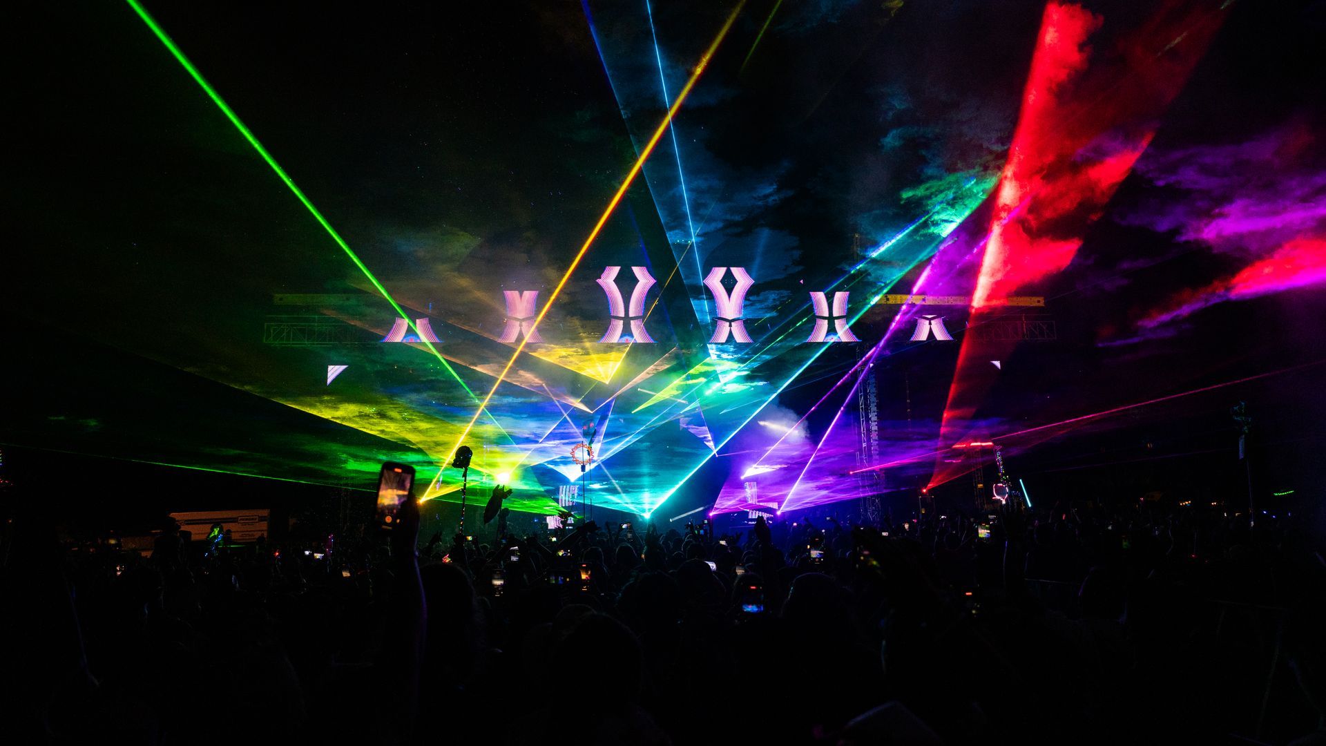 A crowd of people are watching a laser show at a concert.