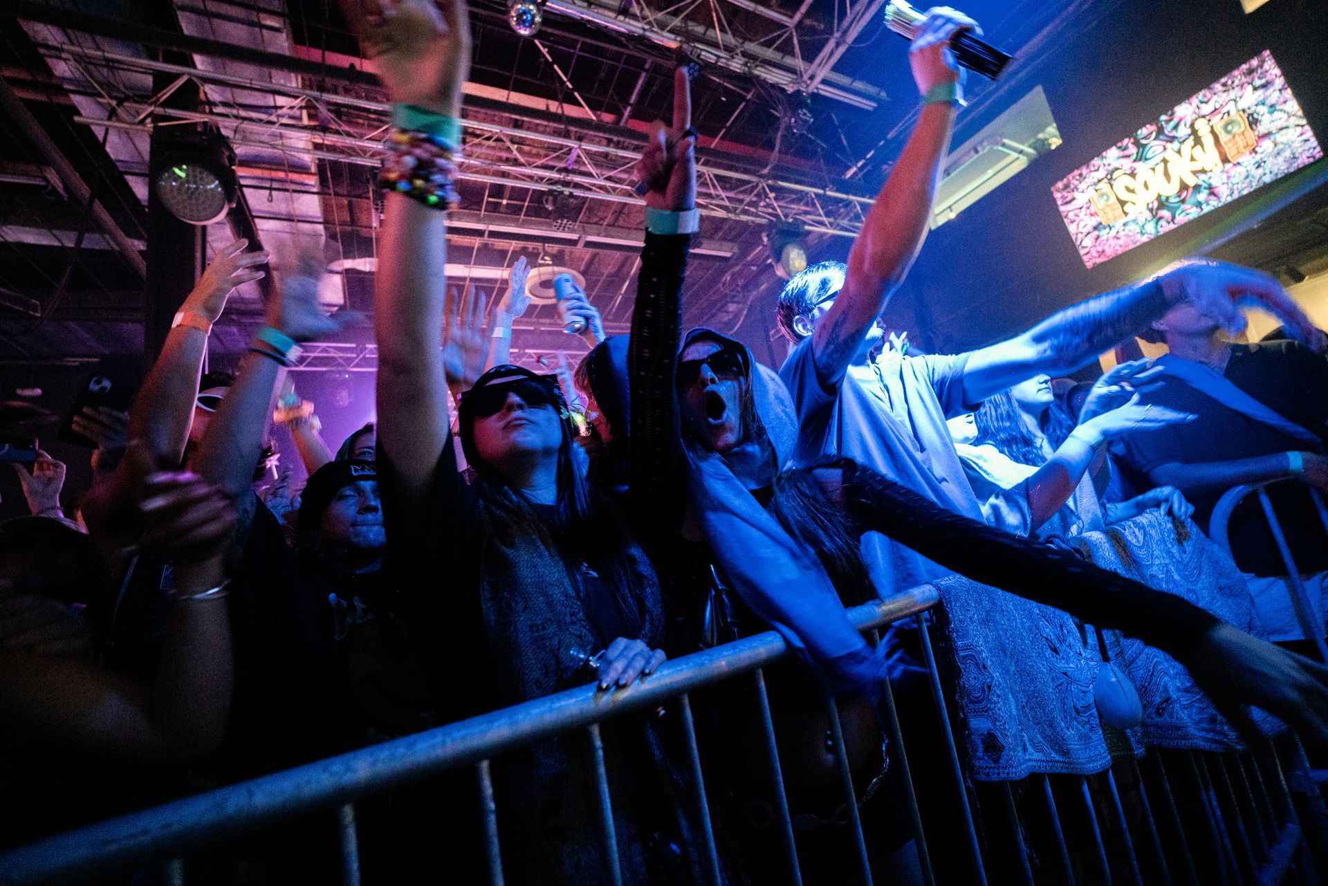 A crowd of people at a concert with their arms in the air