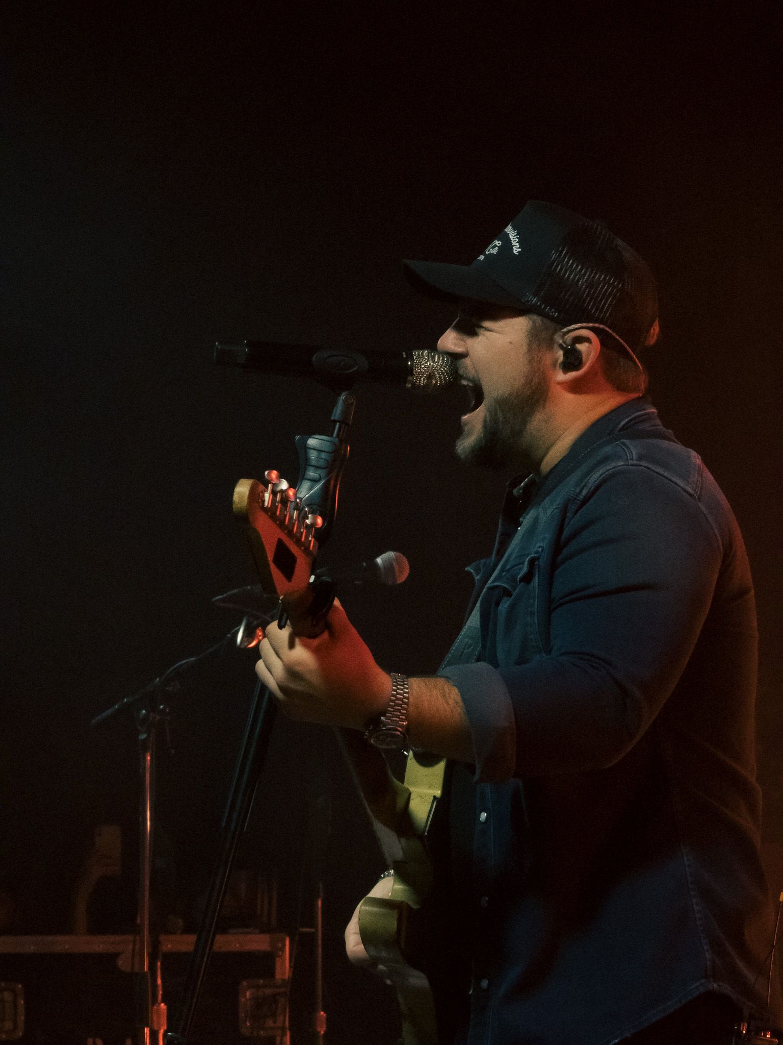 A man singing into a microphone while playing a guitar