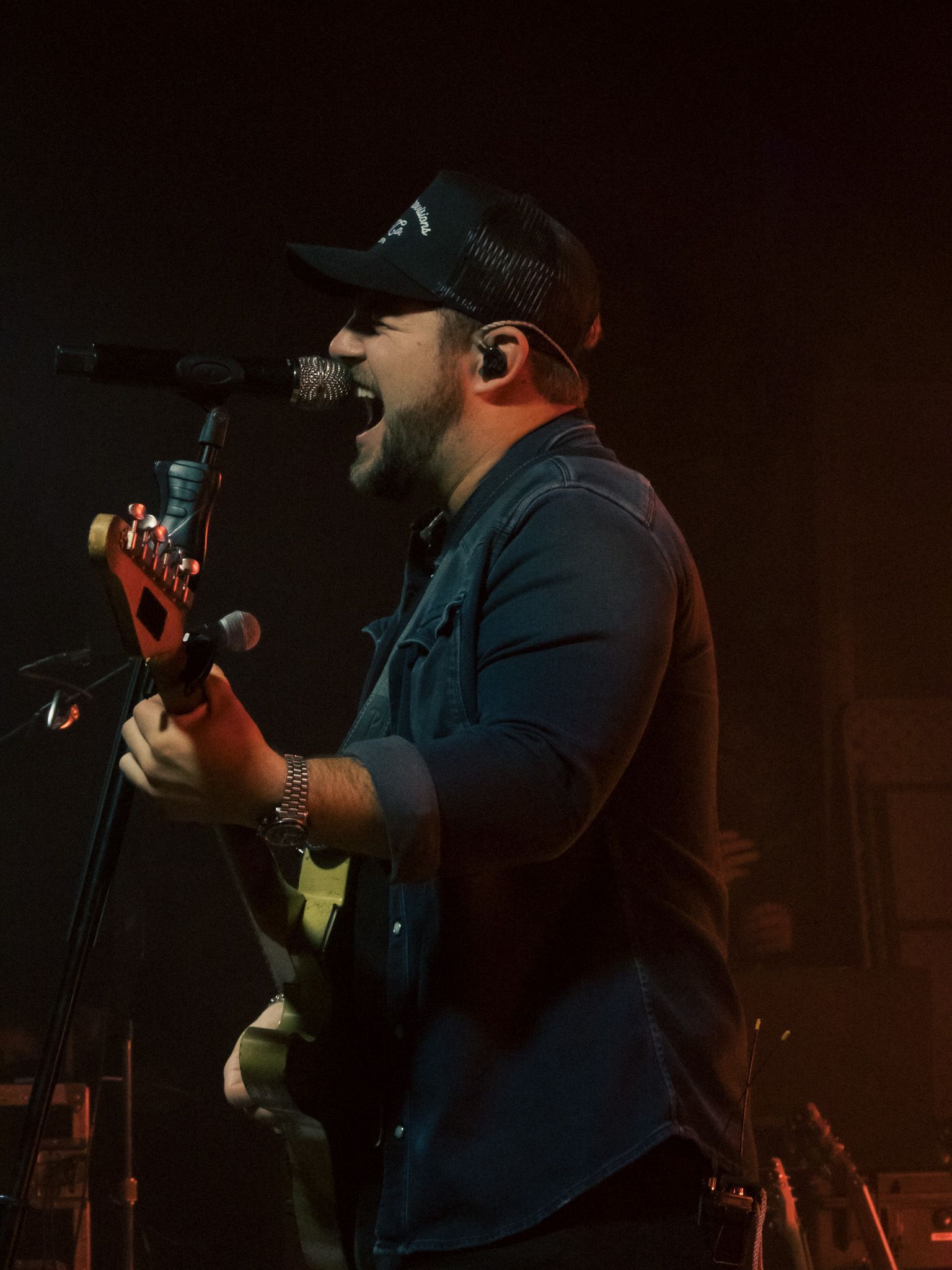 A man is singing into a microphone while playing a guitar.