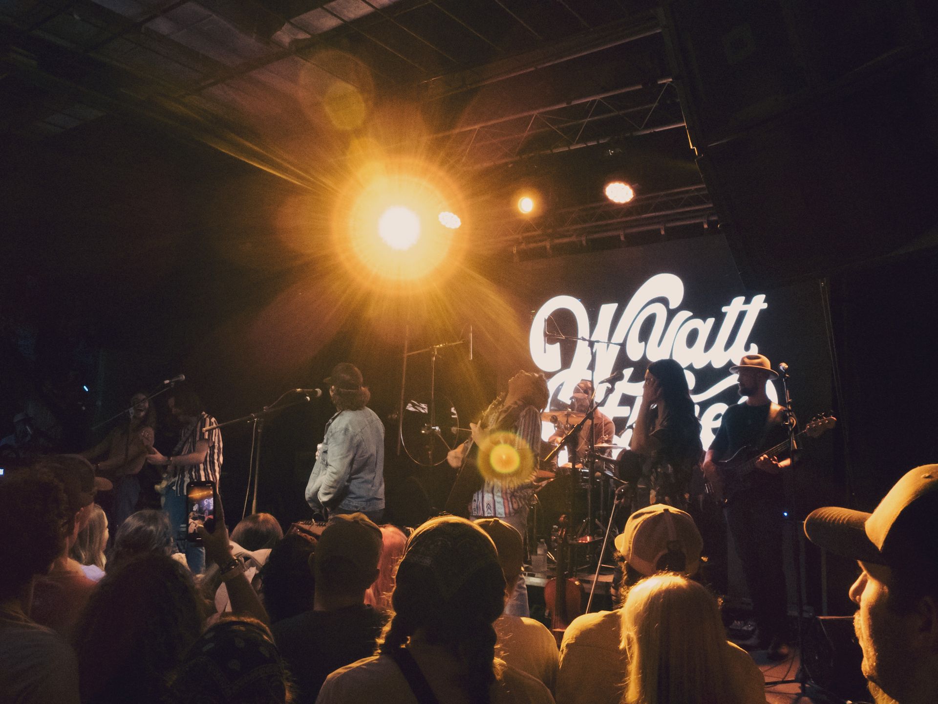 A group of people are sitting in front of a stage that says watt on it