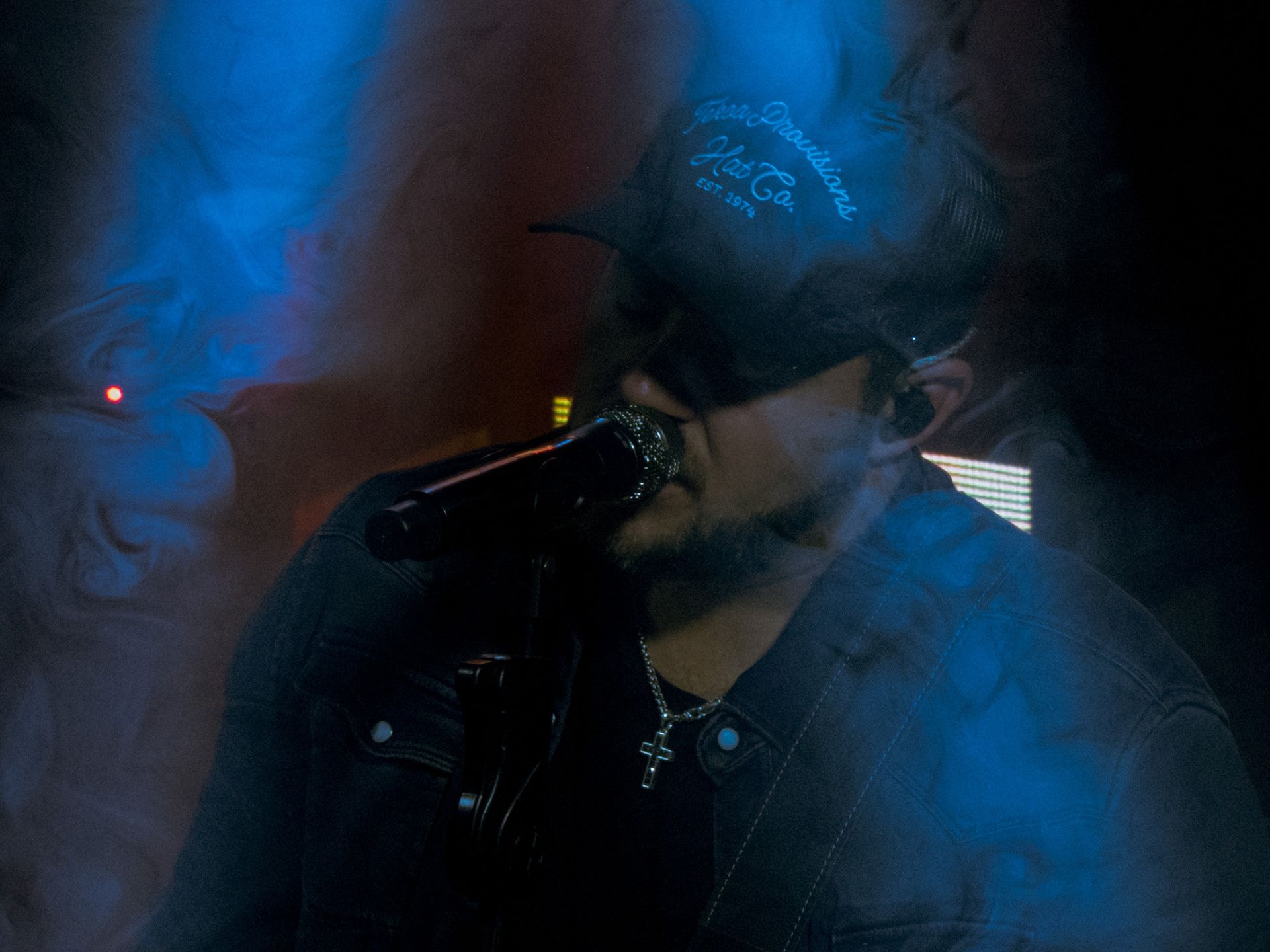 A man is singing into a microphone in a dark room.