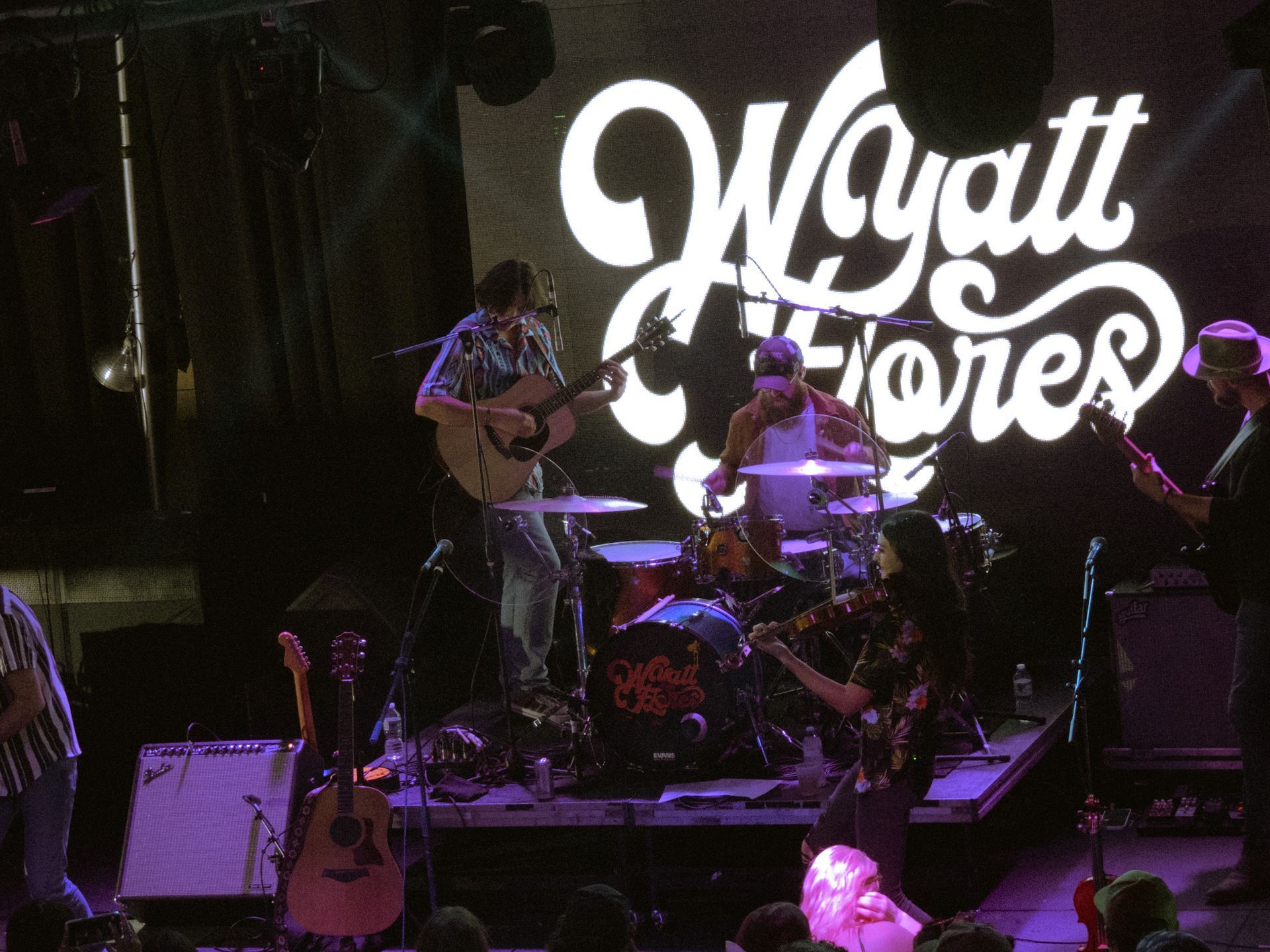 A group of people playing instruments on a stage in front of a sign that says wyatt jones