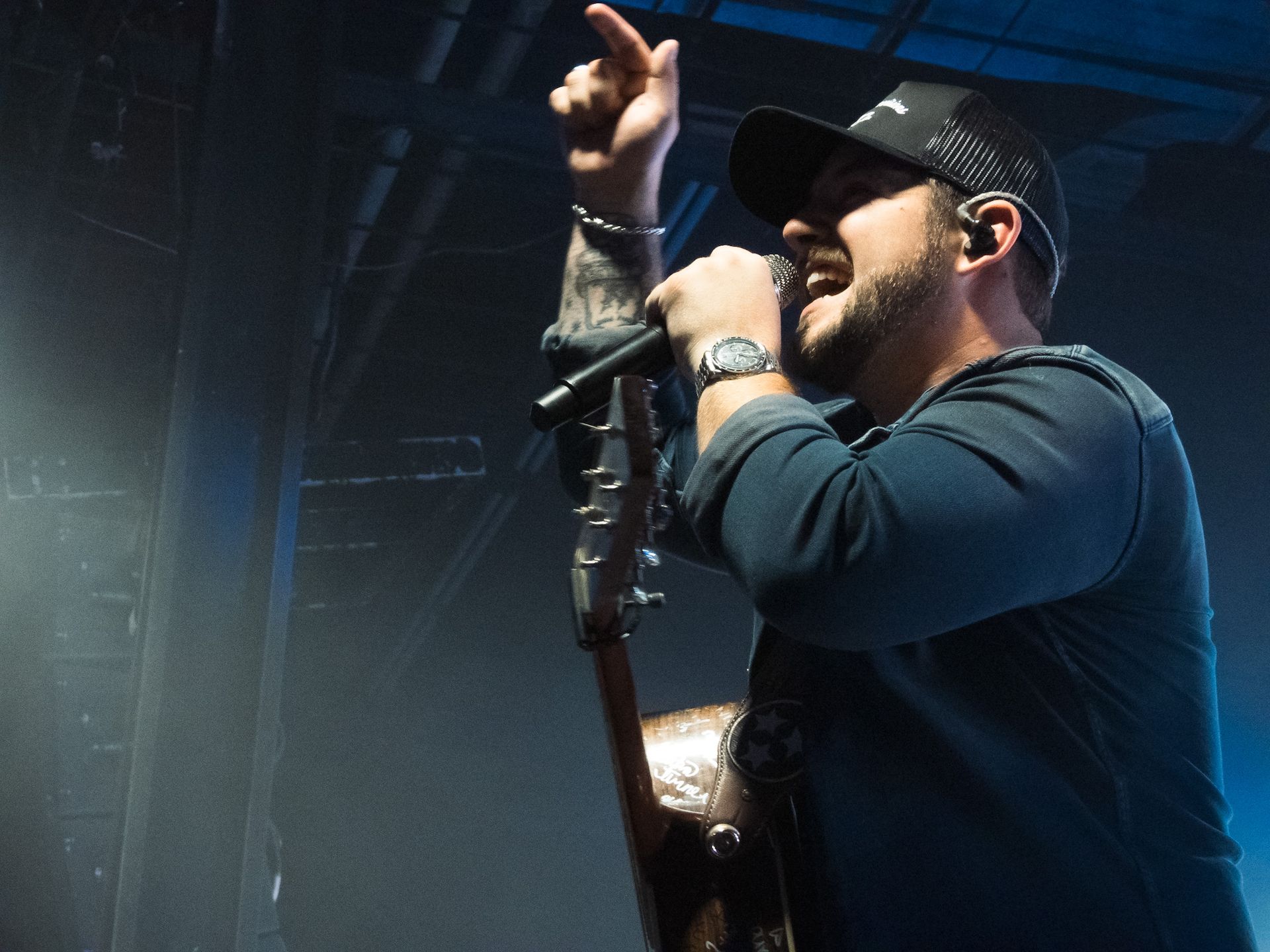 A man is singing into a microphone while holding a guitar.