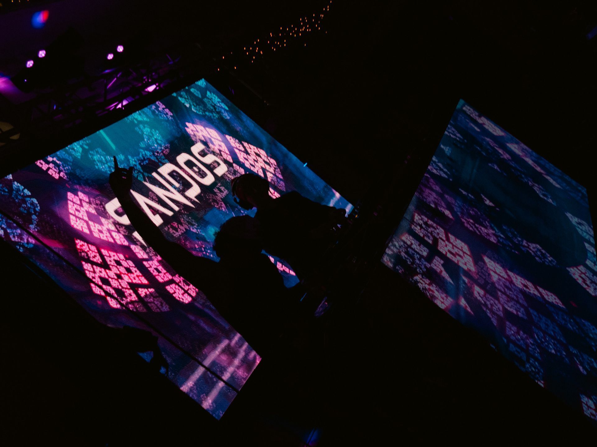 A man is standing in front of a large screen with the word andos on it.