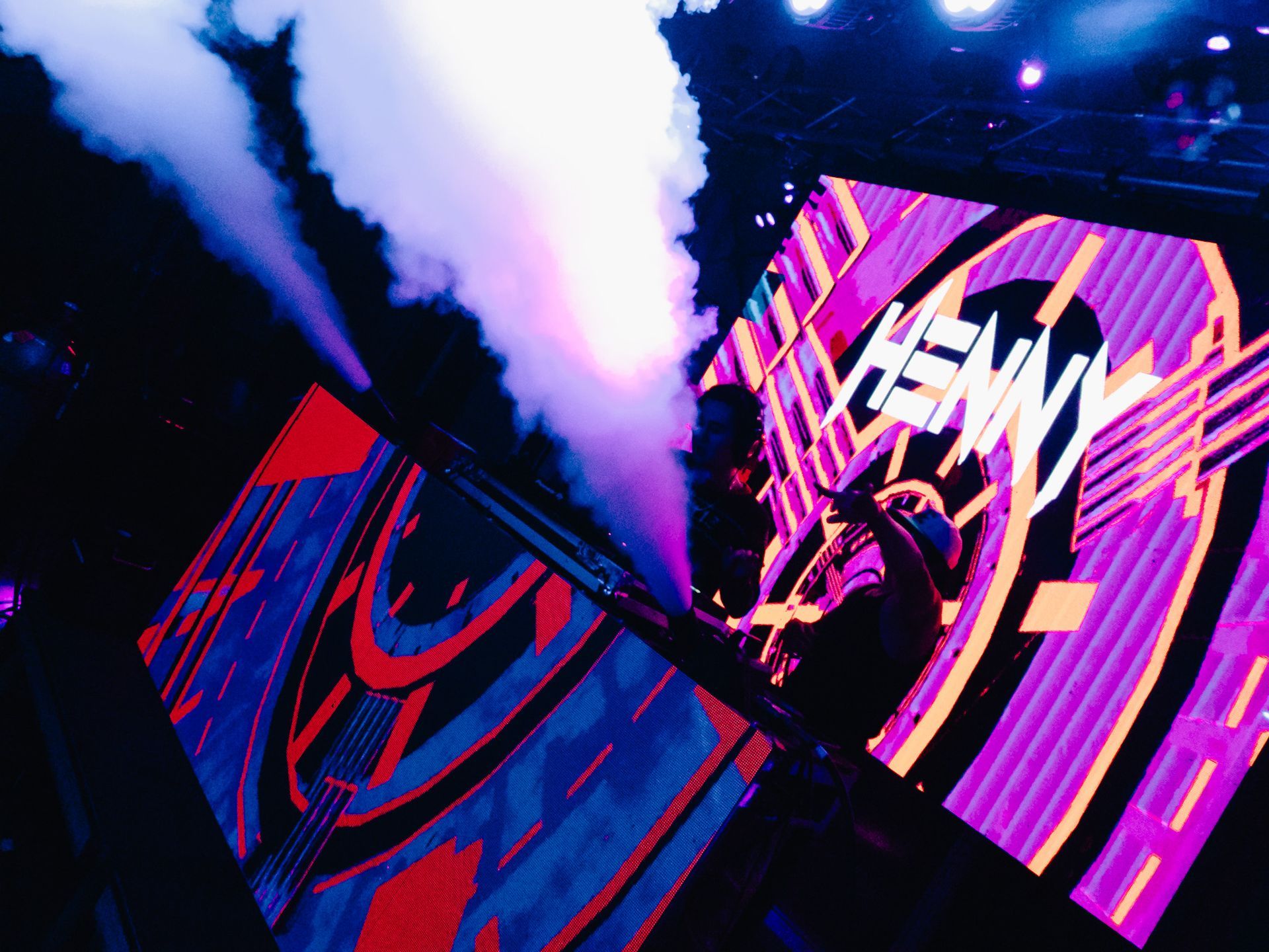 A person is standing in front of a large screen with smoke coming out of it.