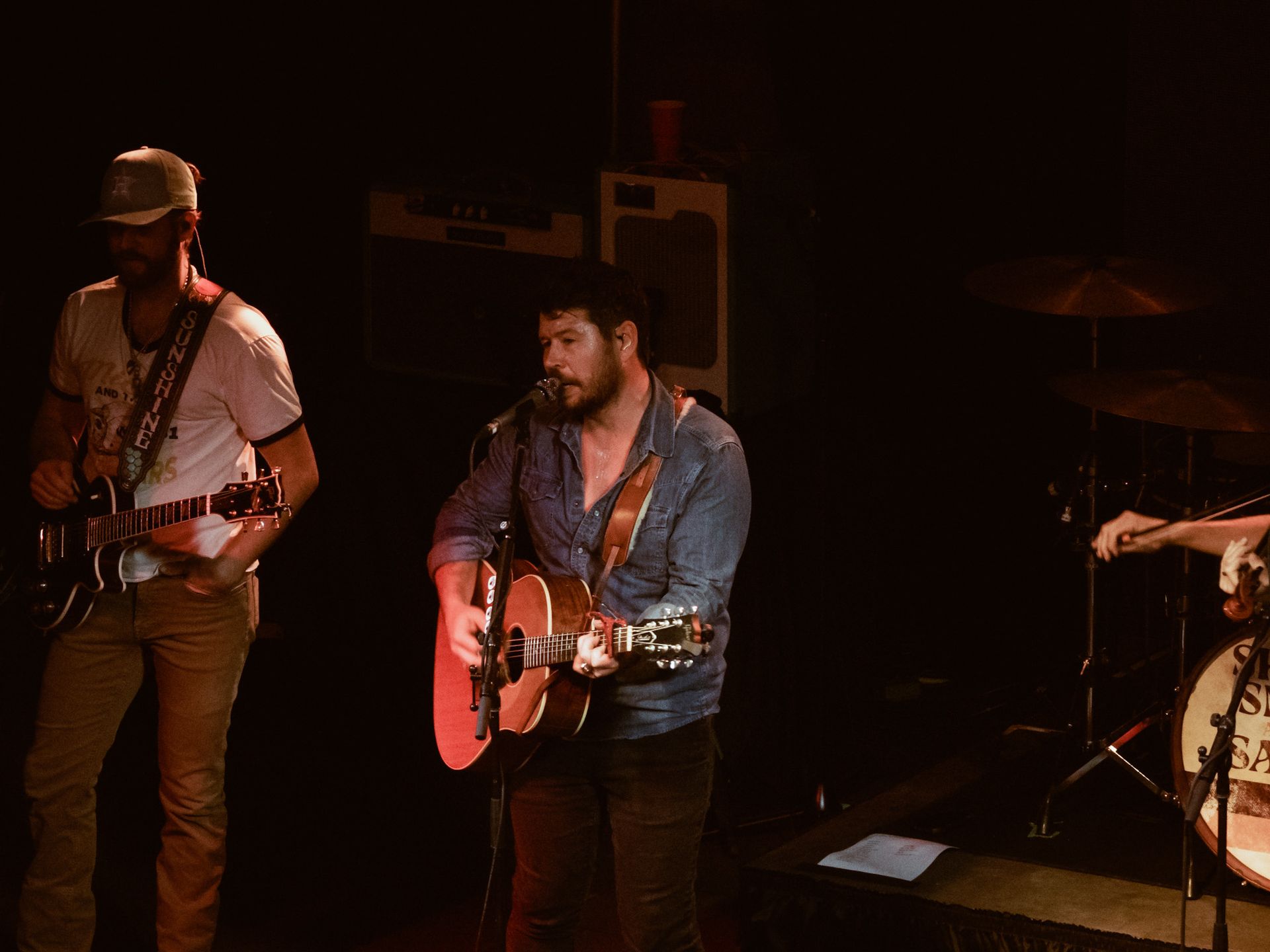 A man is playing a guitar and singing into a microphone on a stage.