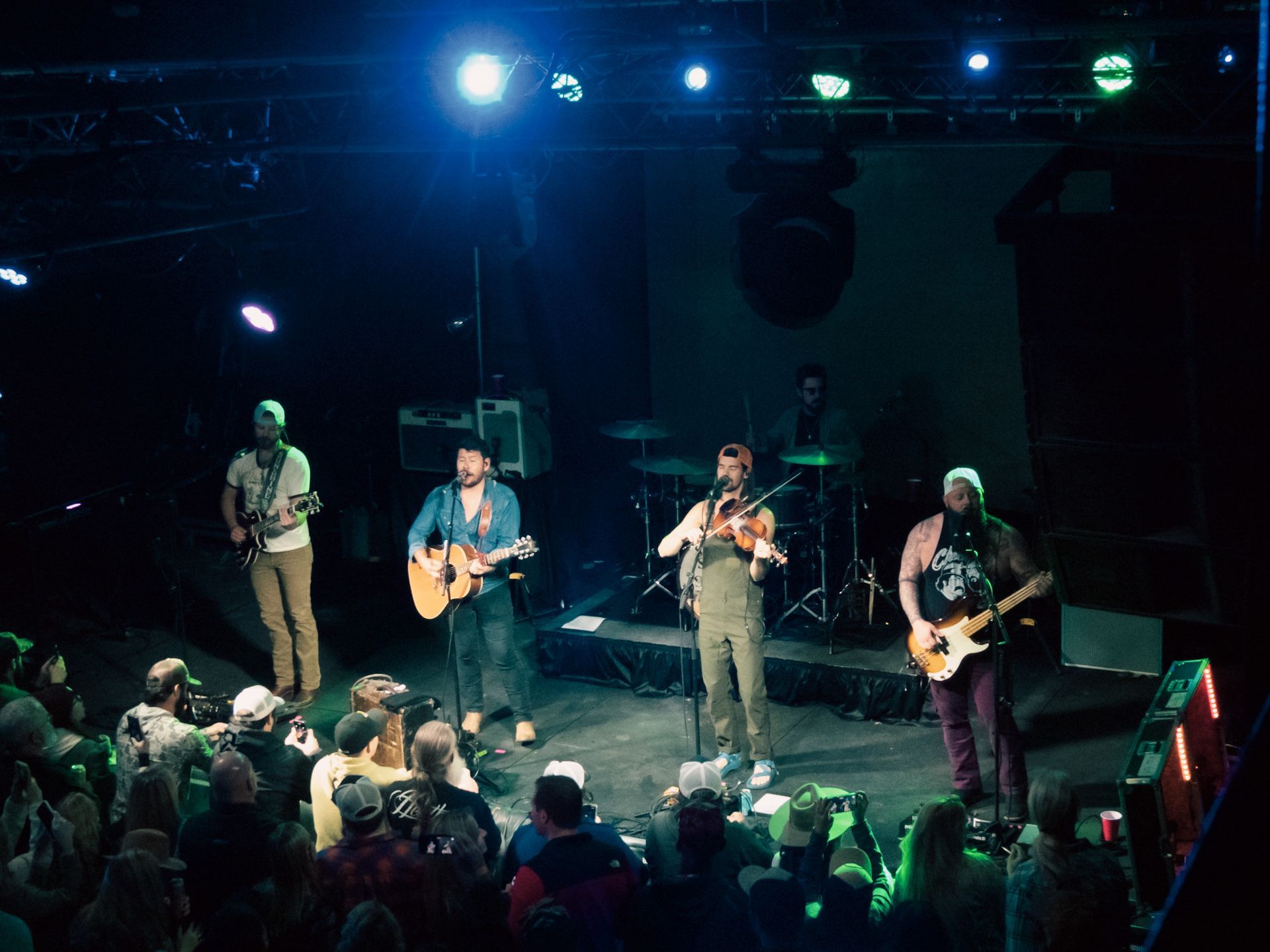A group of men are playing instruments on a stage in front of a crowd.