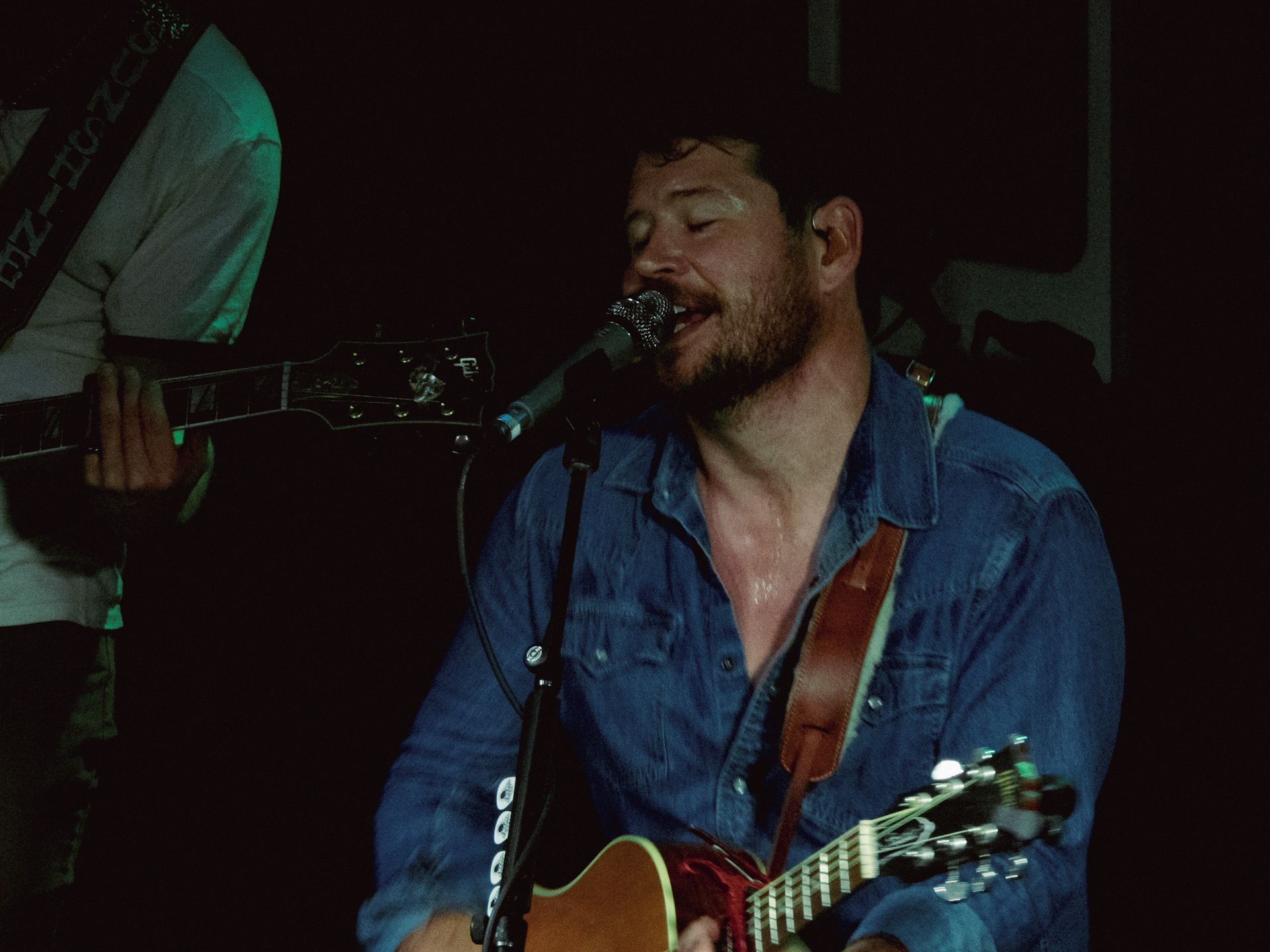 A man is singing into a microphone while playing a guitar.