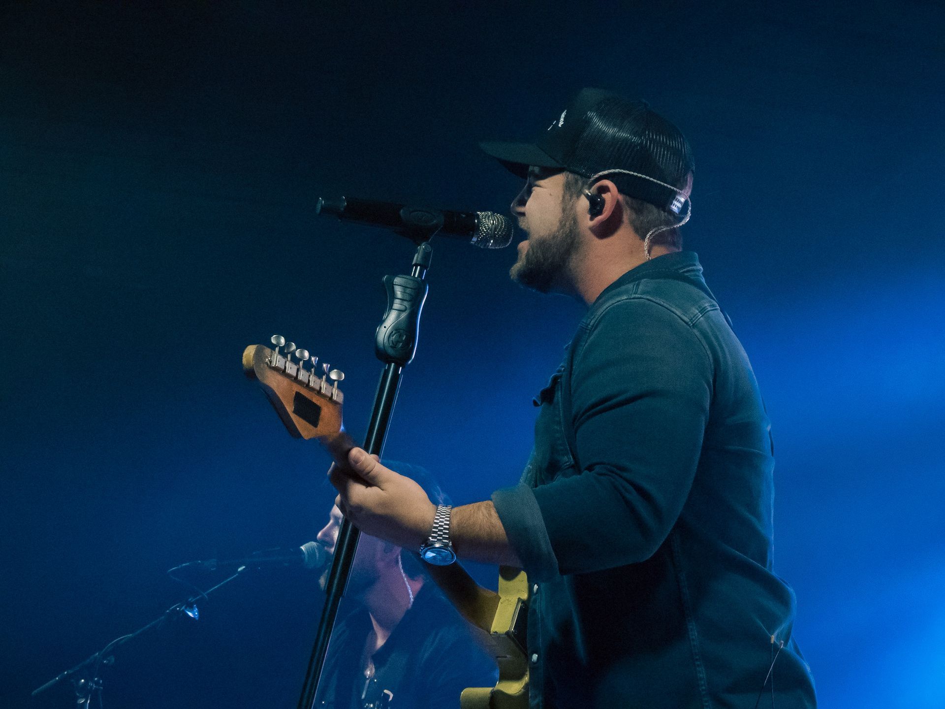 A man is singing into a microphone while playing a guitar.