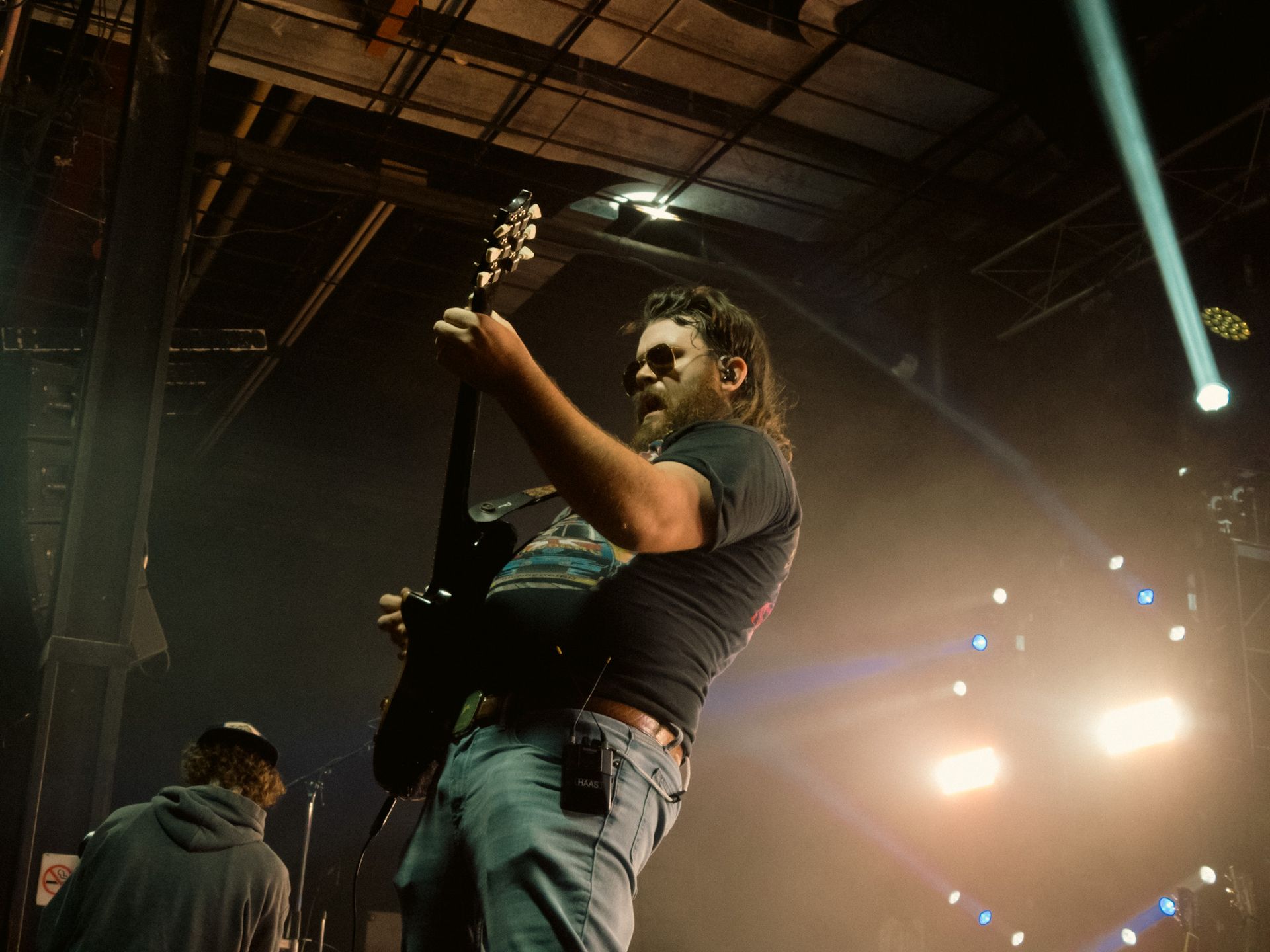 A man is playing a guitar on a stage in a dark room.