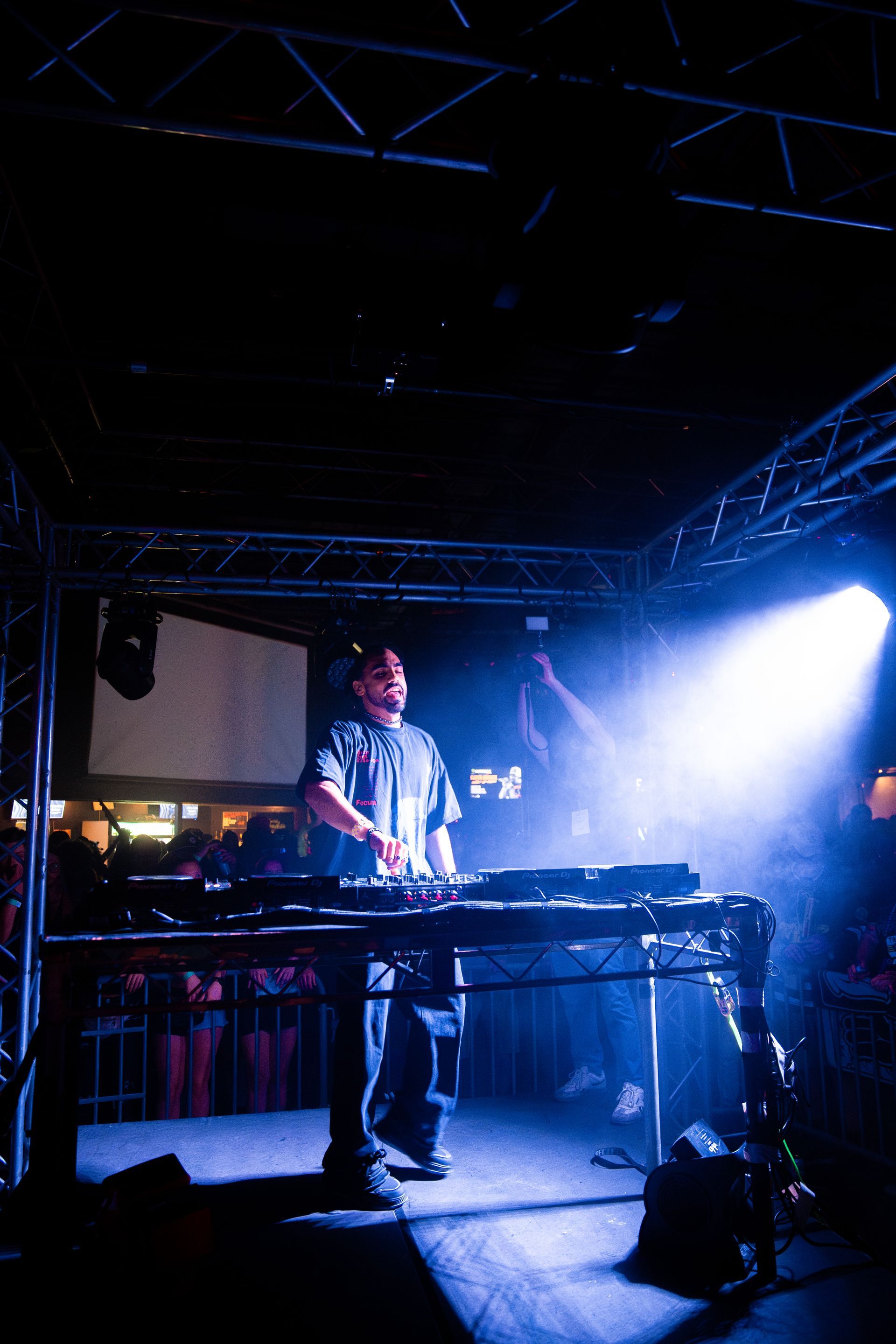A man is playing a keyboard on a stage in a dark room.