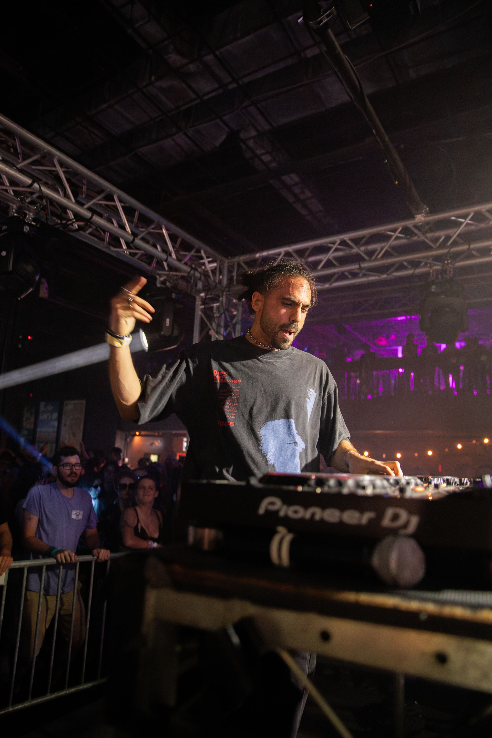A man is standing in front of a pioneer dj in a dark room.