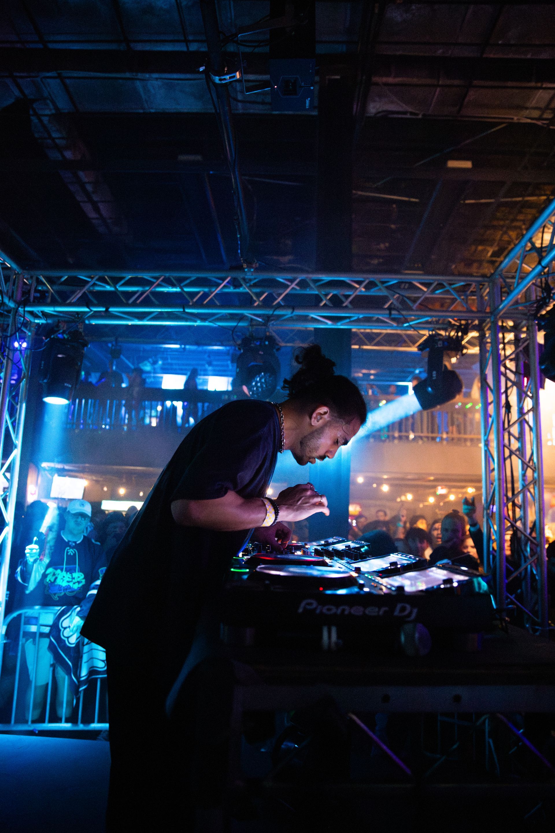 A man is playing a dj set in a dark room.