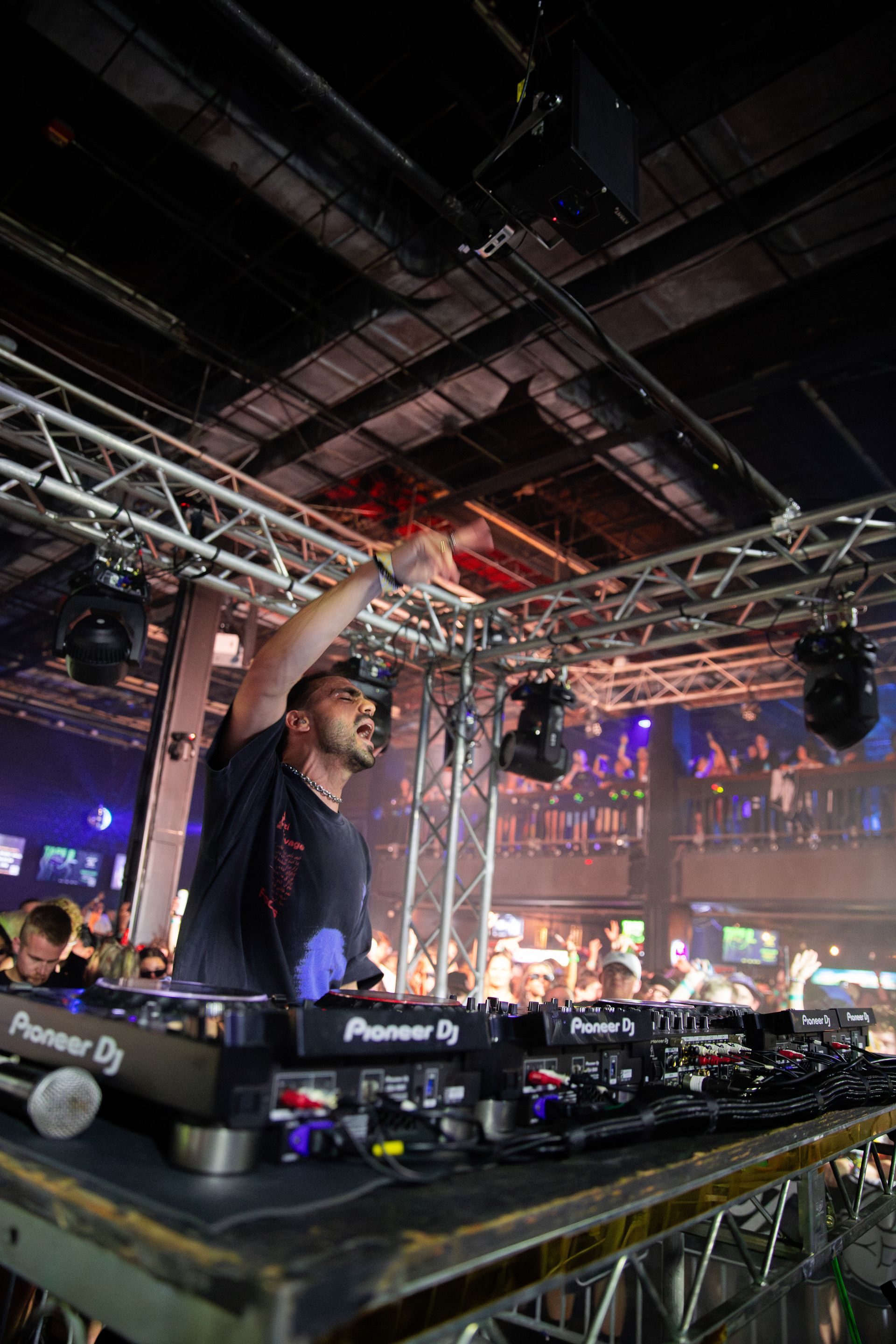 A man is playing a dj set in front of a crowd at a concert.