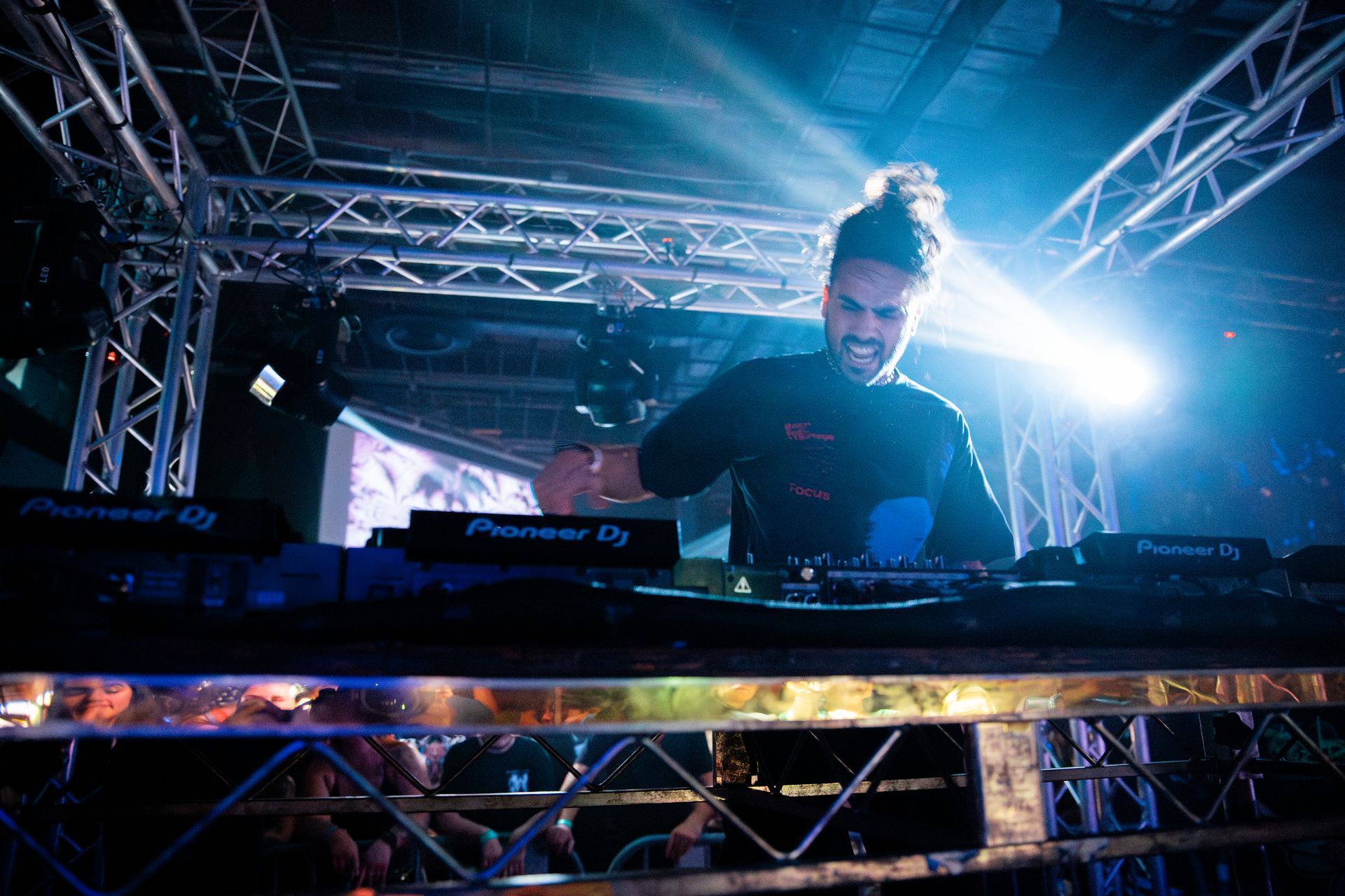 A man is playing a dj set on a stage in a dark room.