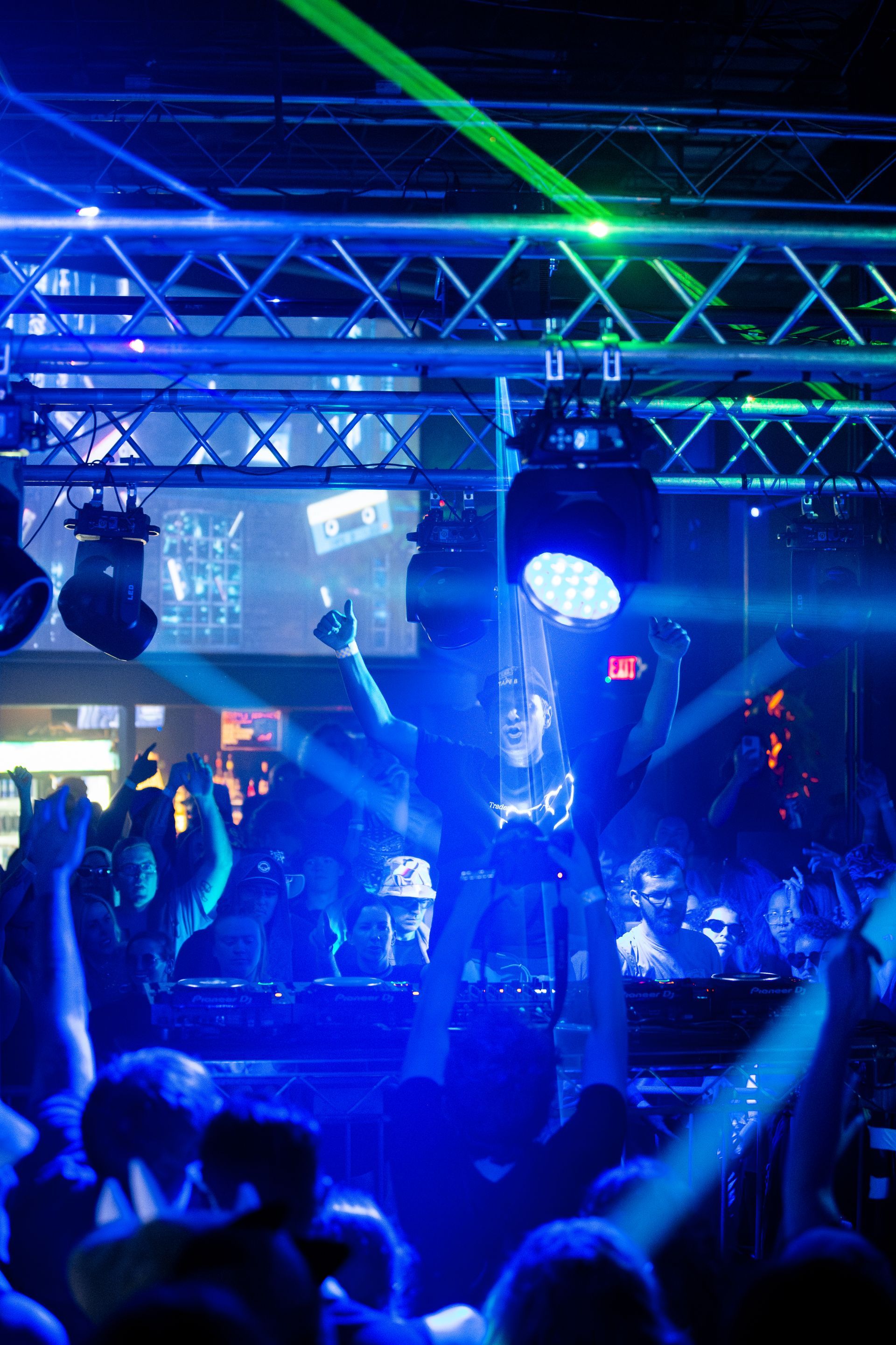 A crowd of people are dancing in a club with blue lights.