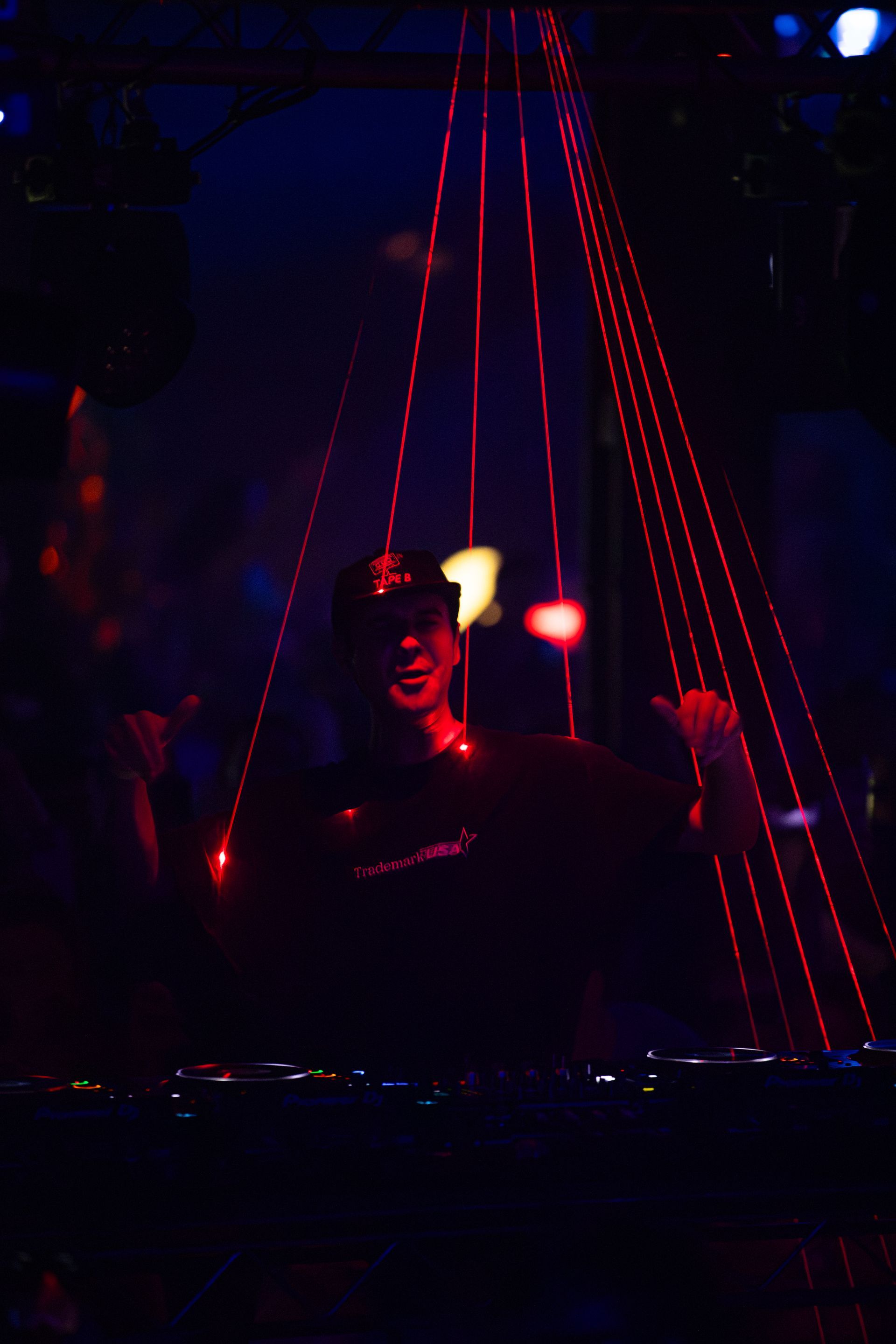 A man is sitting at a table in a dark room with red lights behind him.