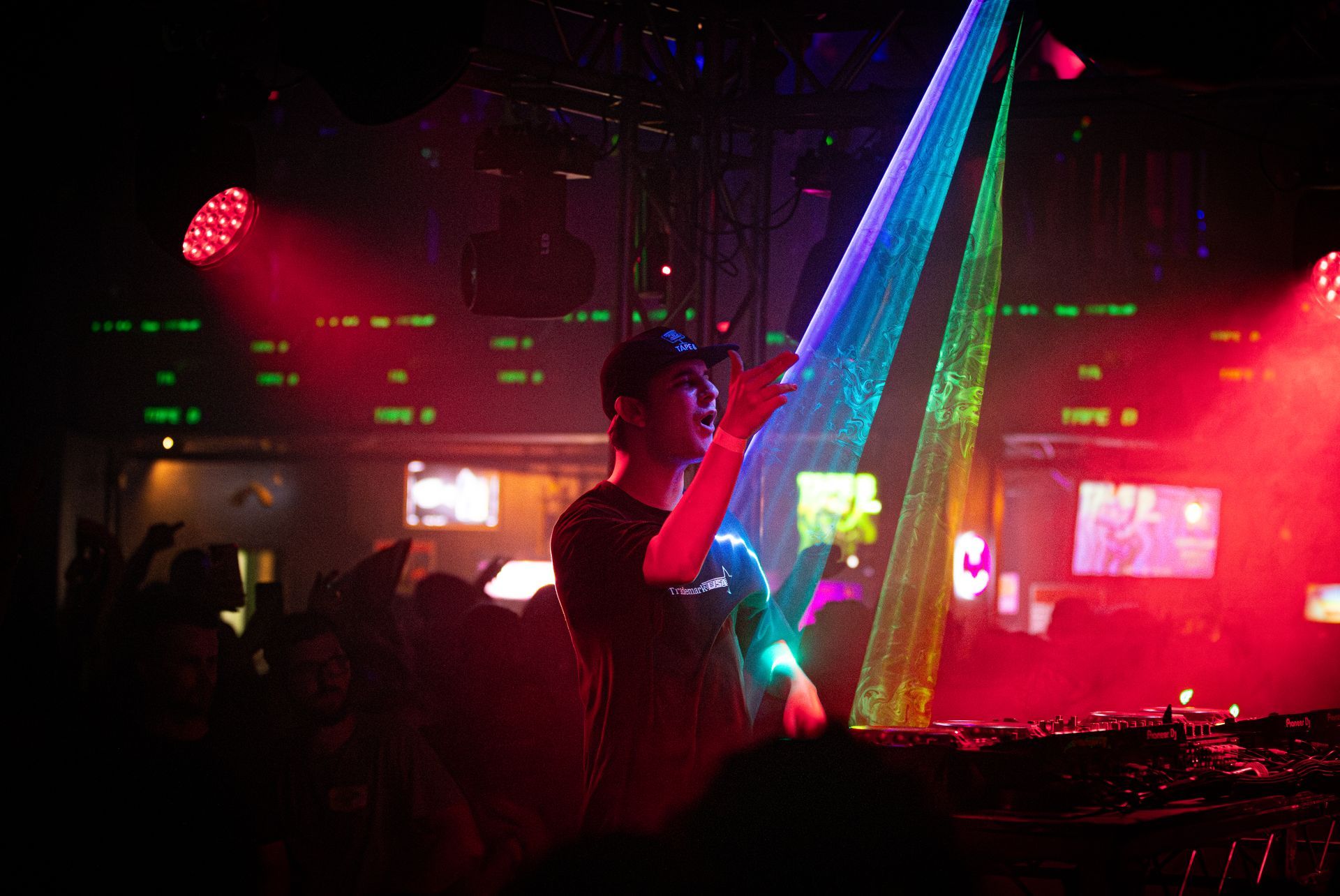 A man is playing a dj set in front of a crowd at a nightclub.