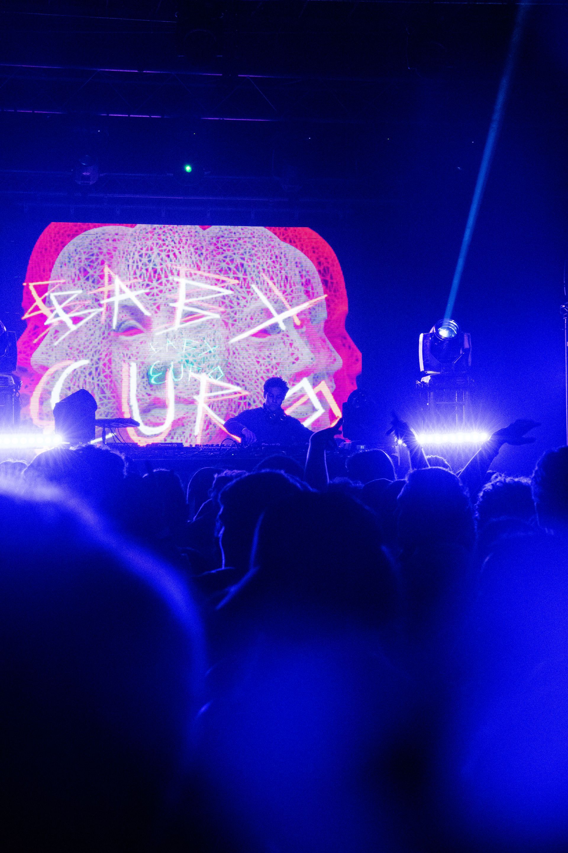 A crowd of people are sitting in front of a stage at a concert.