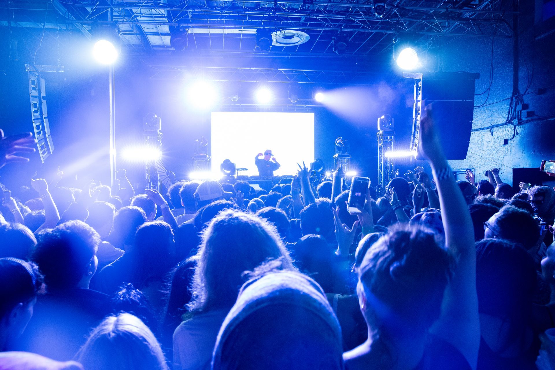 A crowd of people are standing in front of a stage at a concert.